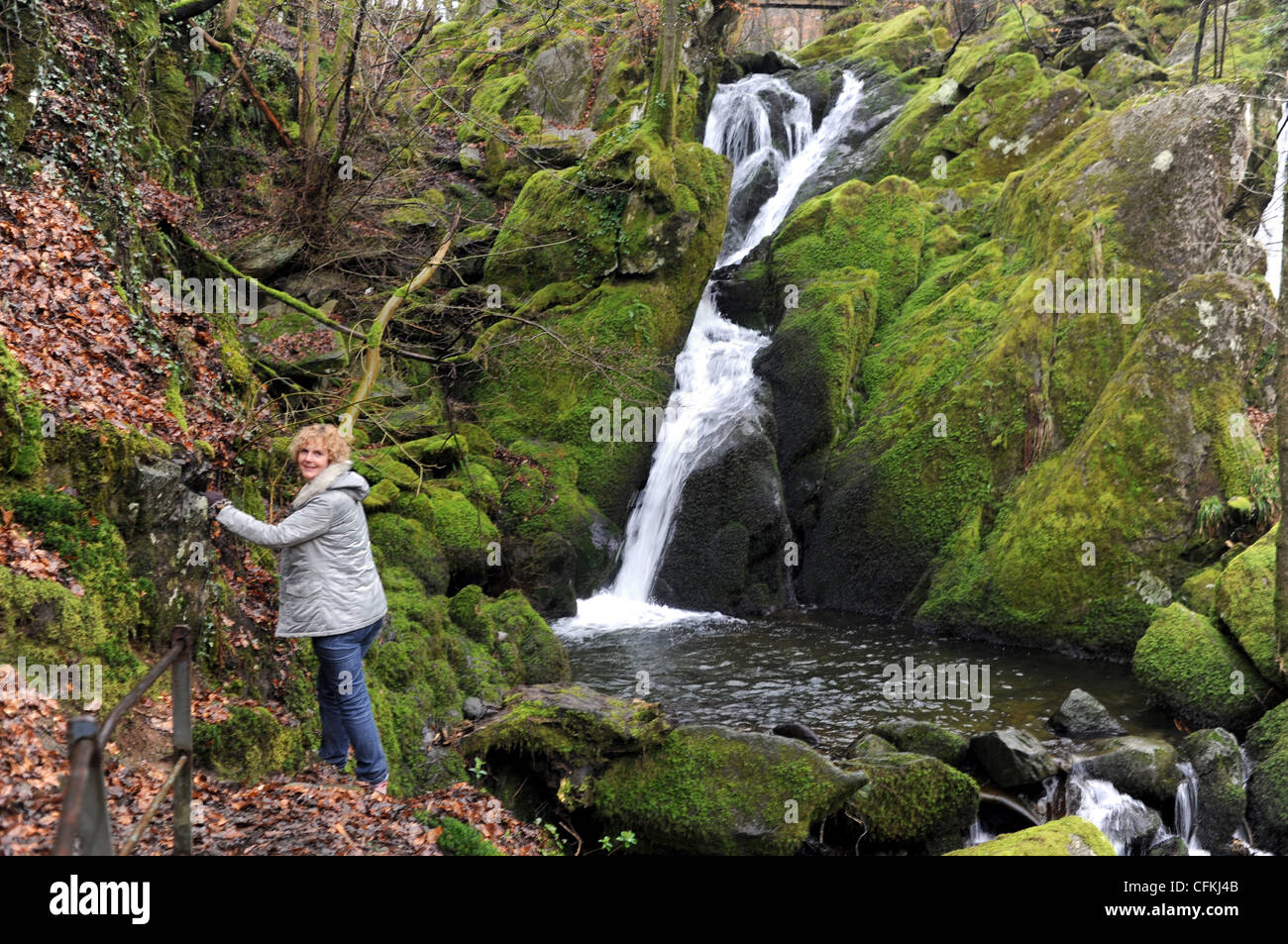 Turista femminile, scendendo da un percorso scivoloso vicino a Stock Ghyll vigore cascate Ambleside Lake District Cumbria Regno Unito Foto Stock