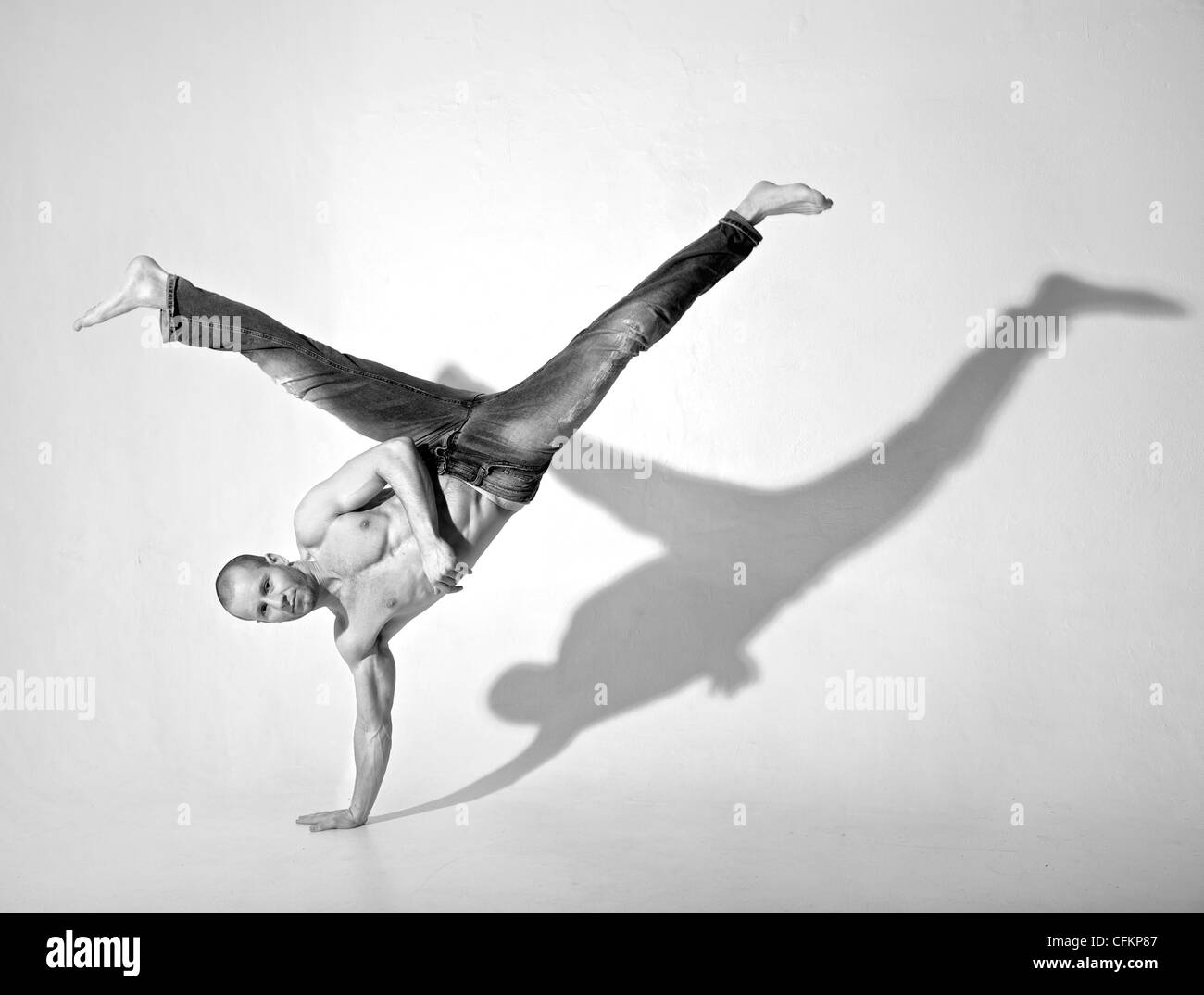 Giovane ballerino maschio eseguire kick mentre si fa un handstand. Girato in studio. Foto Stock
