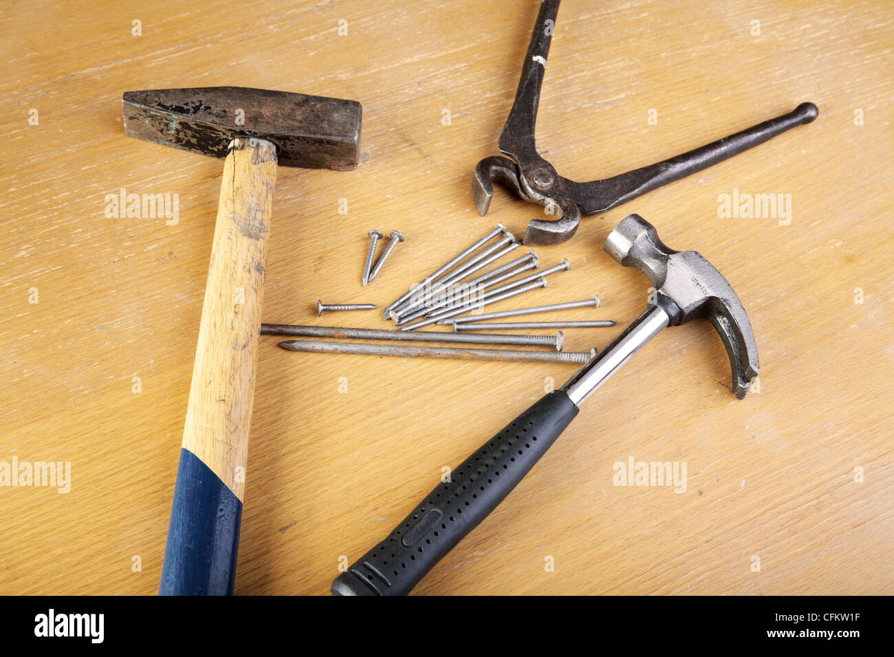 Due martelli e pinze con chiodi su un tavolo Foto Stock