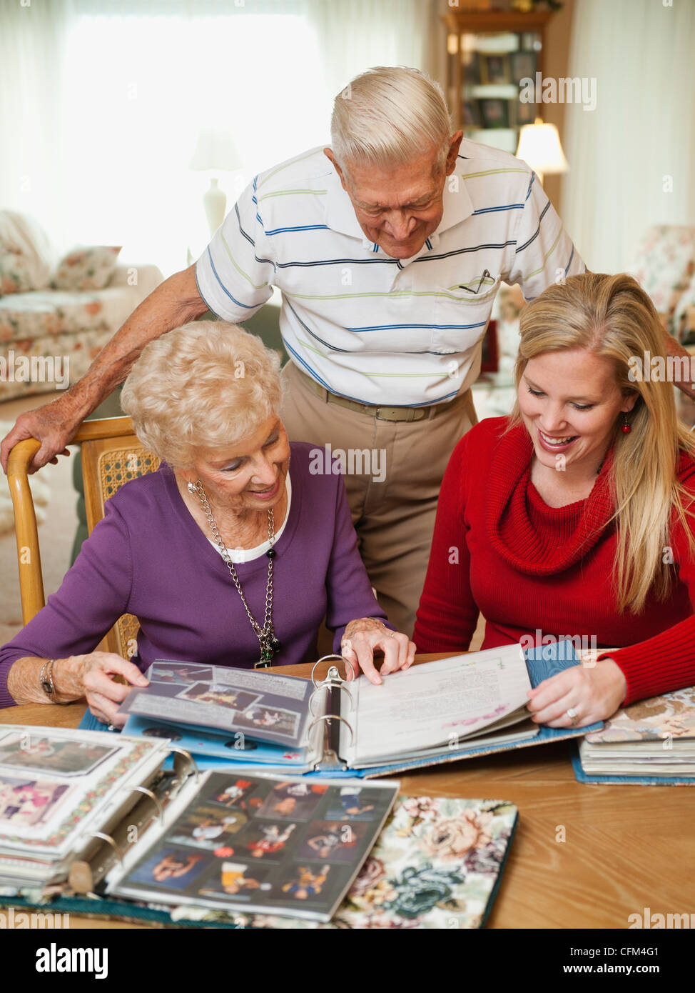 Stati Uniti d'America, Utah, Salt Lake City, coppia Senior e metà donna adulta guarda la famiglia album di ritagli Foto Stock