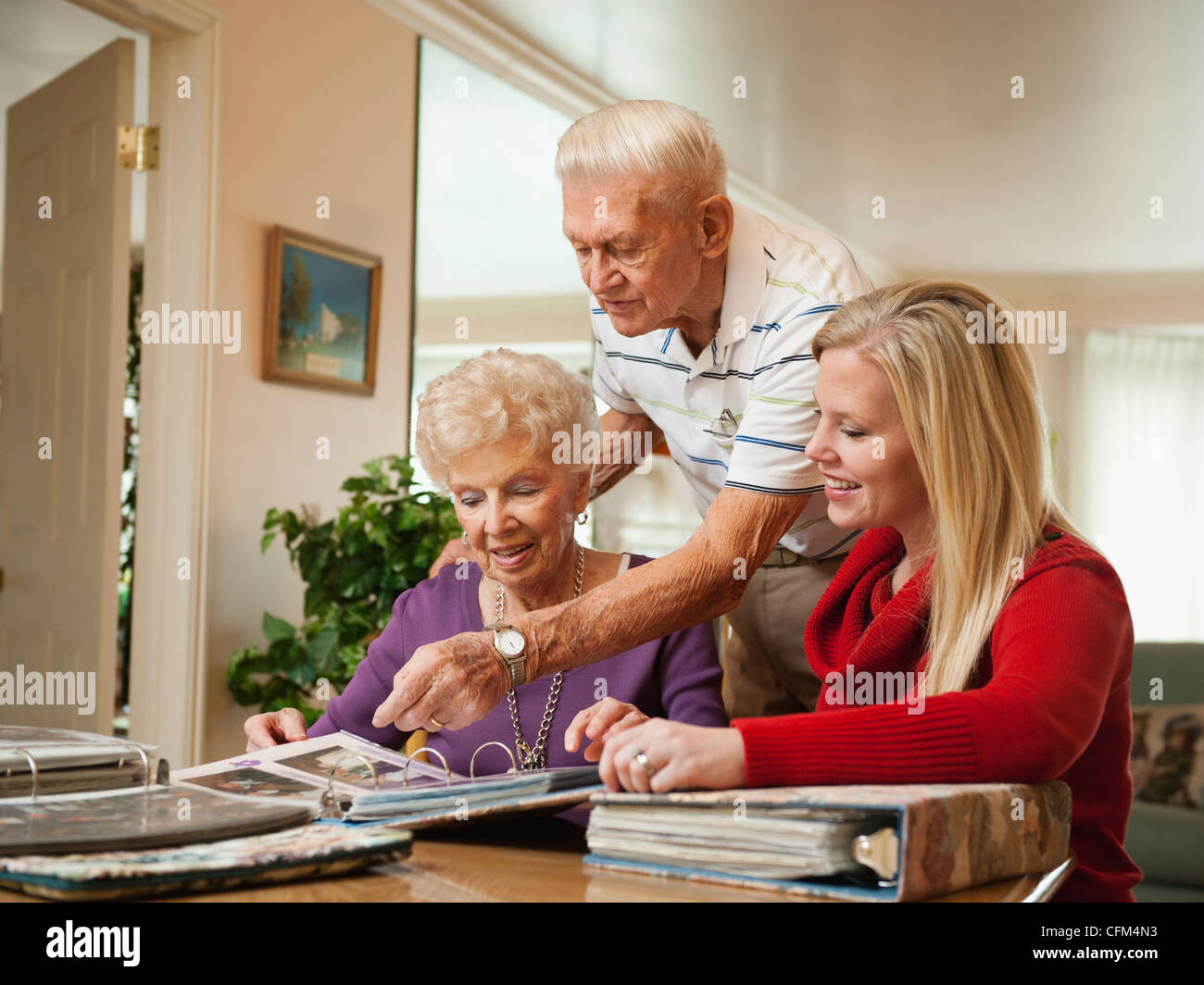 Stati Uniti d'America, Utah, Salt Lake City, coppia Senior e metà donna adulta guarda la famiglia album di ritagli Foto Stock