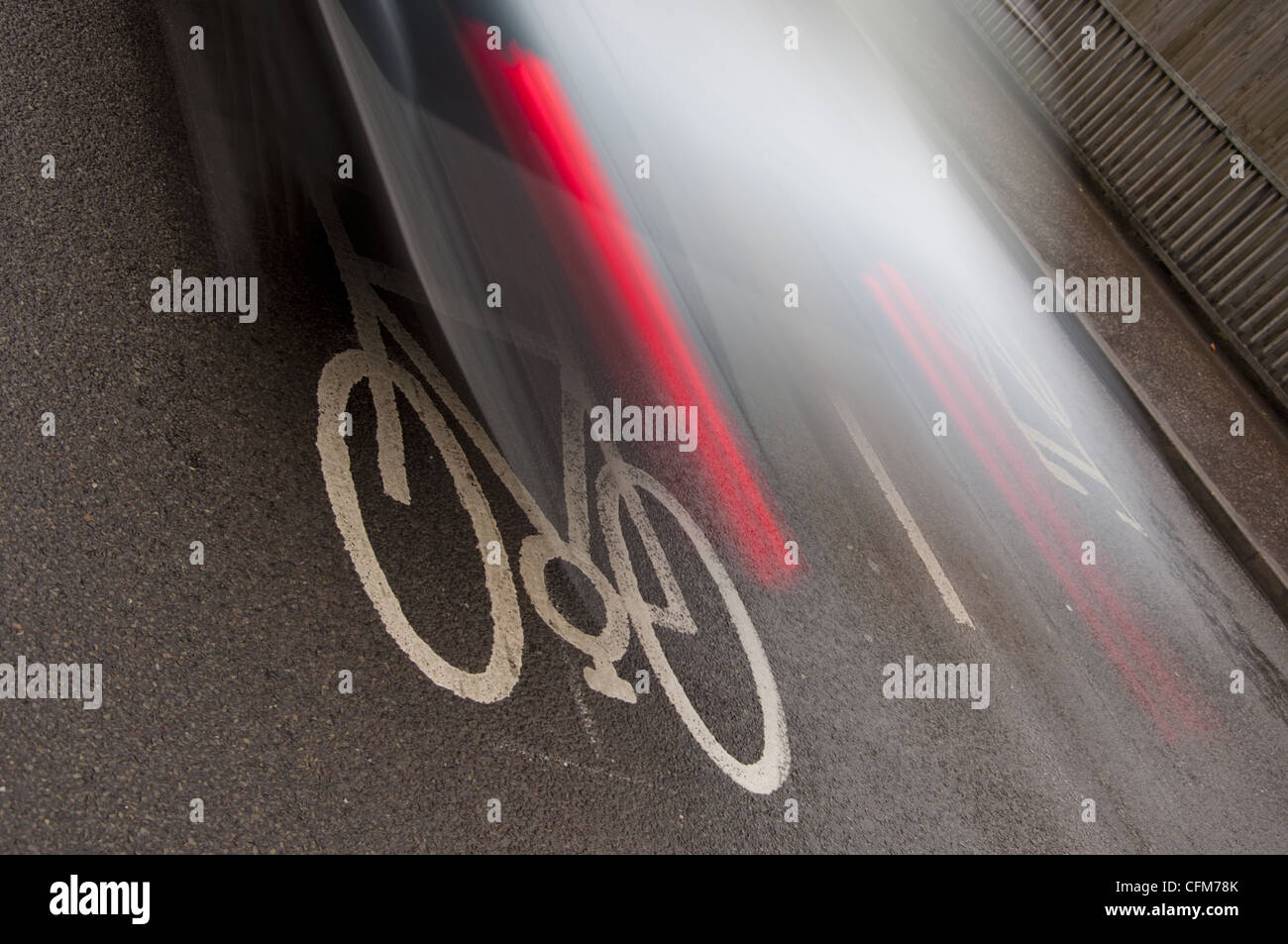 In bici su strada simbolo di marcatura in pista ciclabile con sfocate auto in movimento Foto Stock