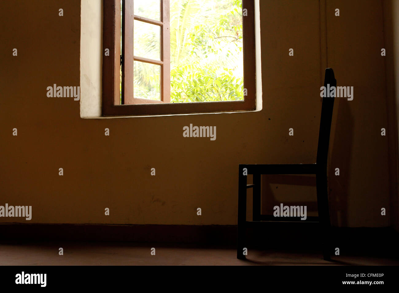 Una sedia vuota da una finestra aperta Foto Stock