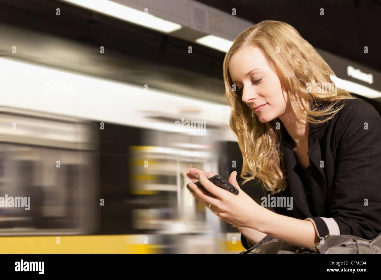Stati Uniti, California, Los Angeles, donna l'invio dei messaggi di testo sulla stazione della metropolitana Foto Stock