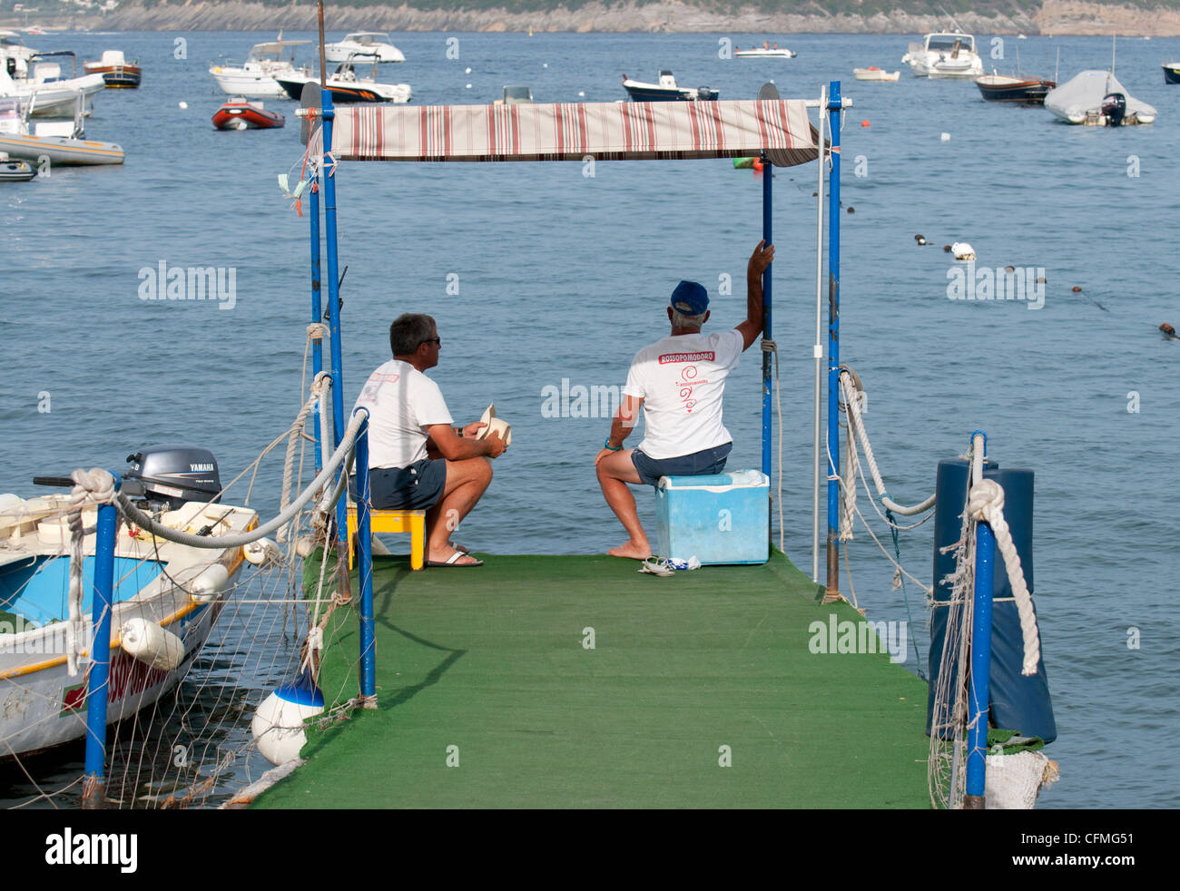 Due membri del personale dai taxi boat company Rossopomodoro seduto su di un molo sull isola di Ischia in Italia Foto Stock