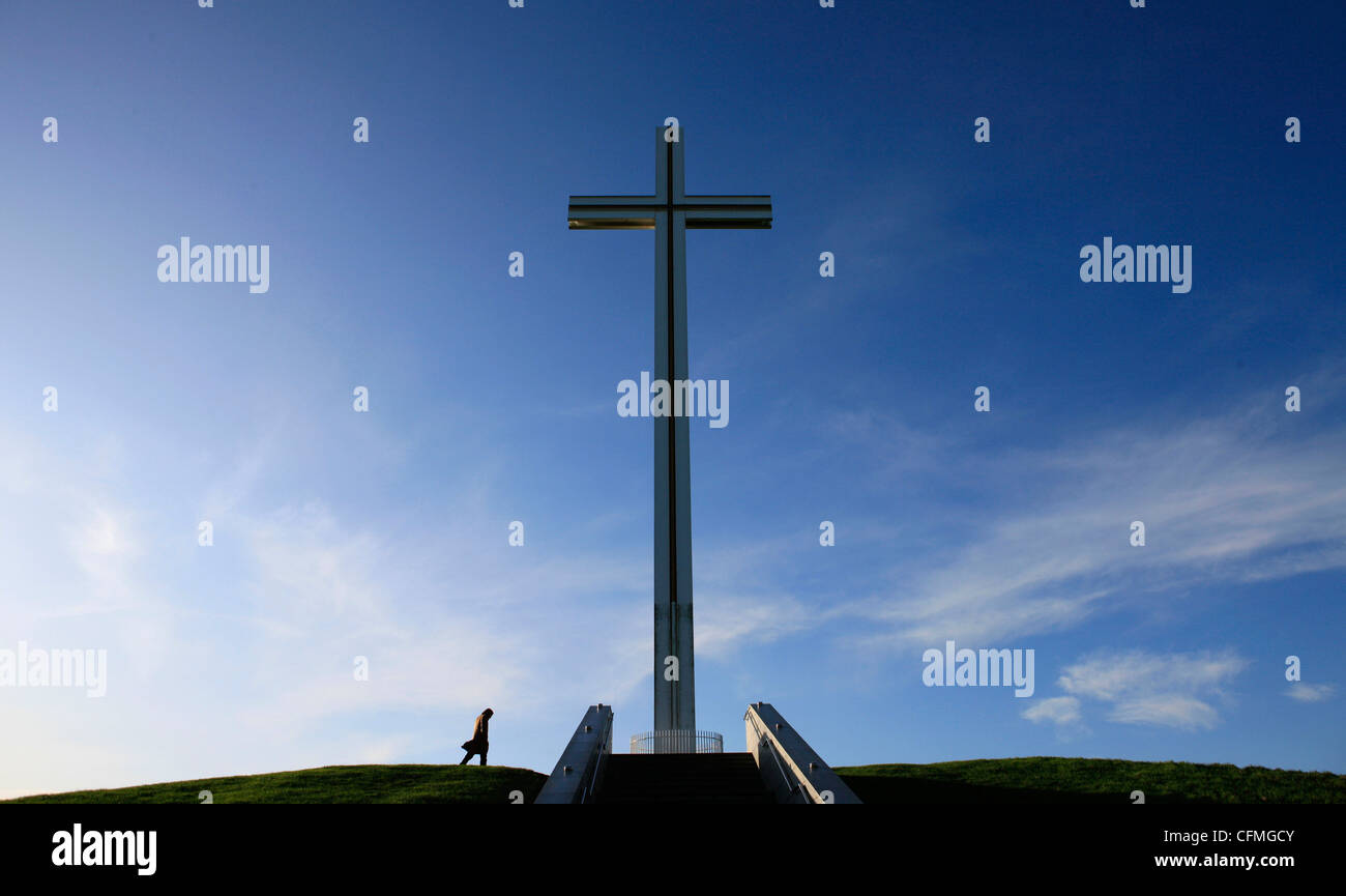 Una persona che cammina accanto a una grande croce in Phoenix Park di Dublino Foto Stock