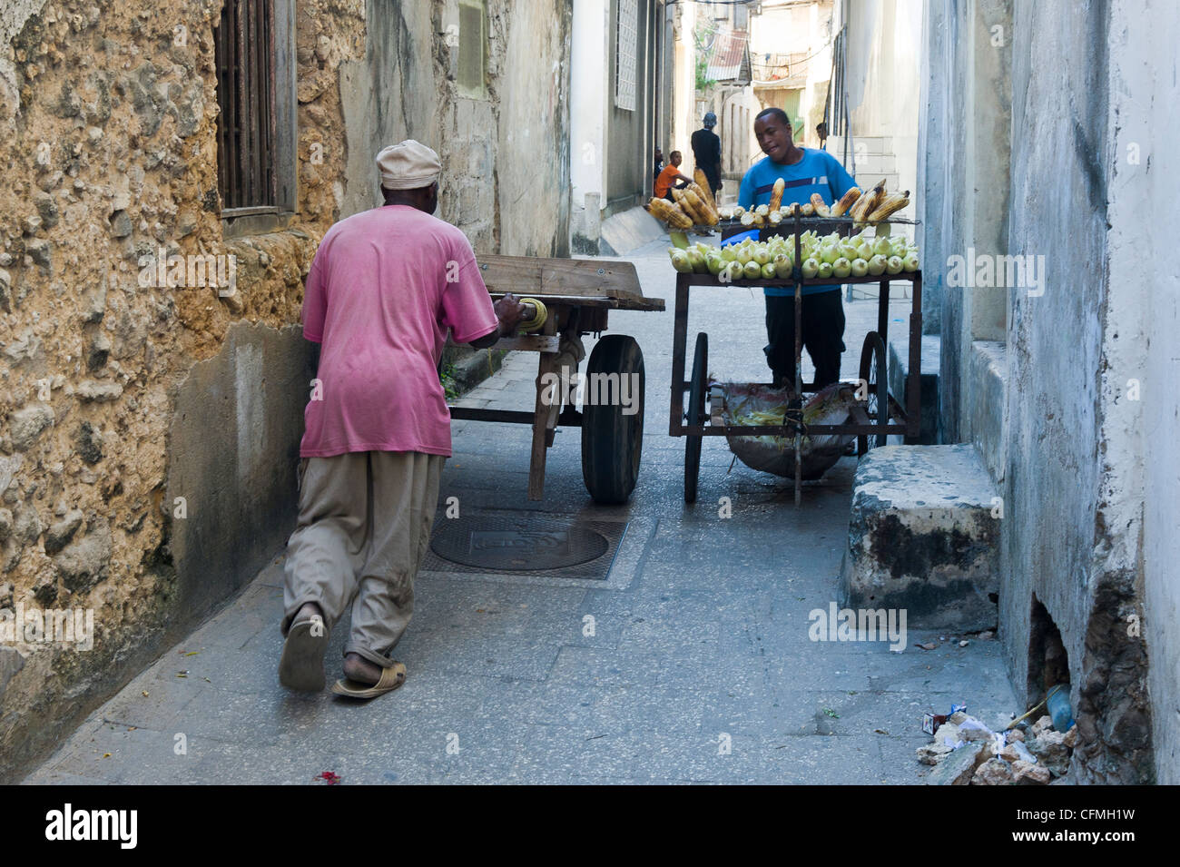 Gli uomini di spingere carrelli attraverso gli stretti vicoli di Stone Town Zanzibar Tanzania Foto Stock