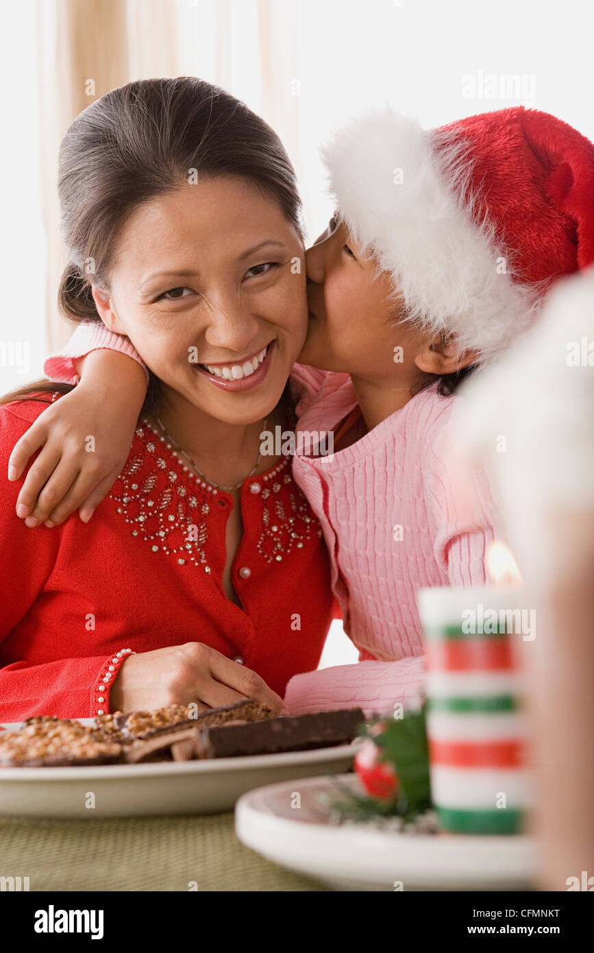 Stati Uniti, California, Los Angeles, ragazza (10-11) indossa Santa hat kissing madre Foto Stock