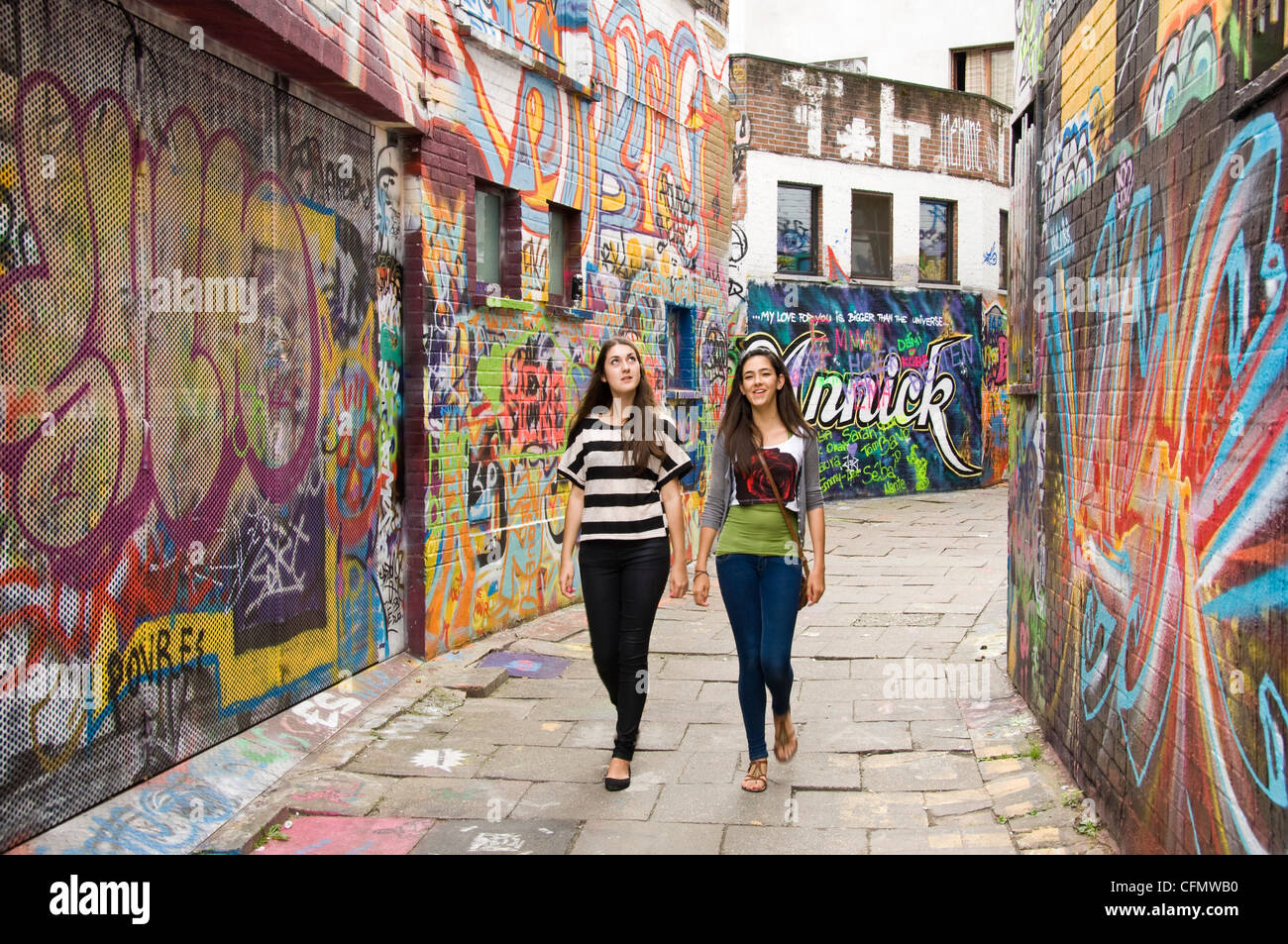 Vista orizzontale di Graffiti Vicolo Werregaran Straat a Gand, con due giovani ragazze guardando le illustrazioni di graffiti sulle pareti Foto Stock