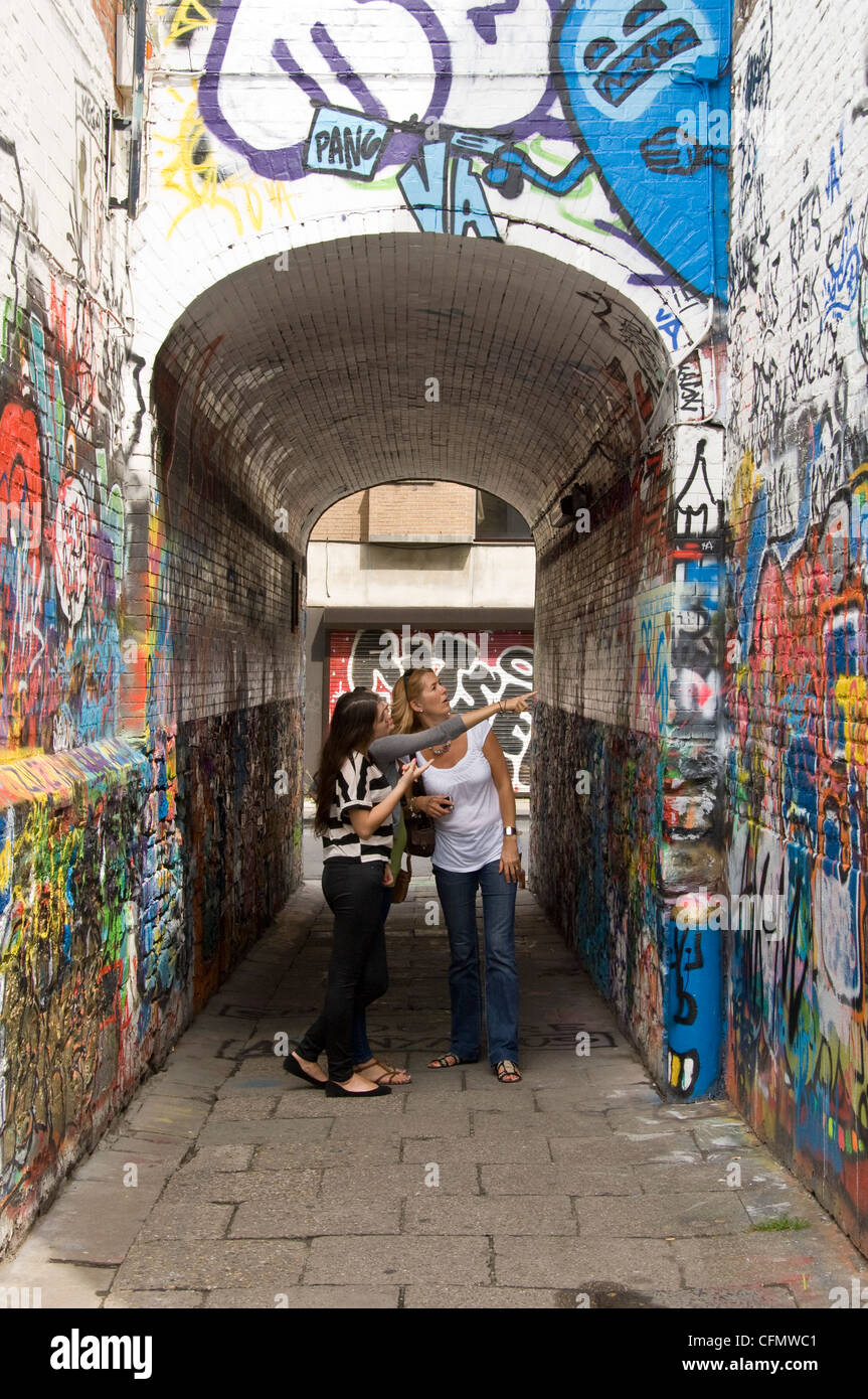 Vista verticale di turisti guardando grafitti artwork che coprono ogni superficie giù il vicolo di graffiti, Werregaran Straat, a Gand. Foto Stock