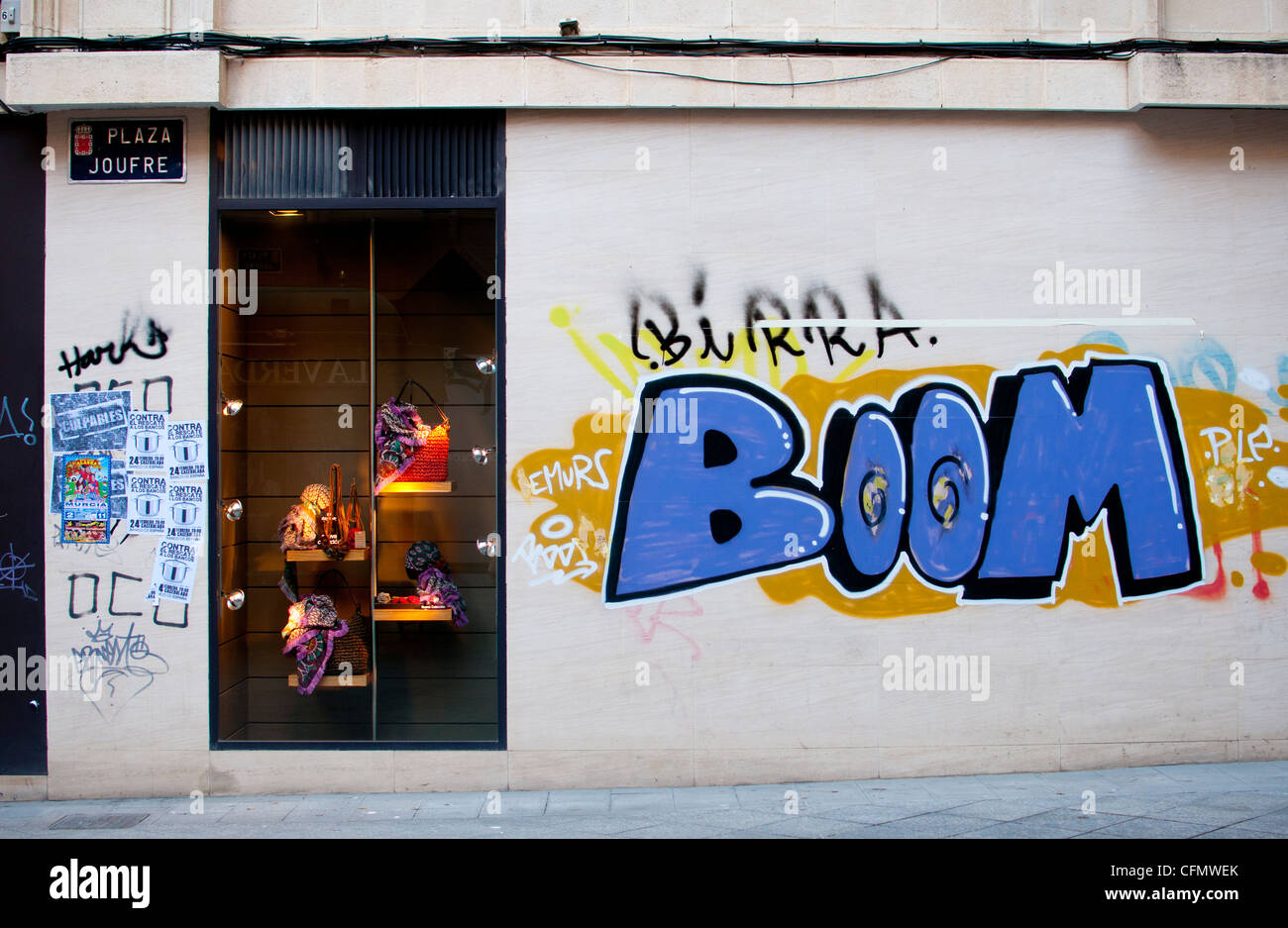 Elegante e alla moda di vetrina in Spagna con graffiti e trasandato poster. Una scena urbana in contrasto due modi di vita Foto Stock