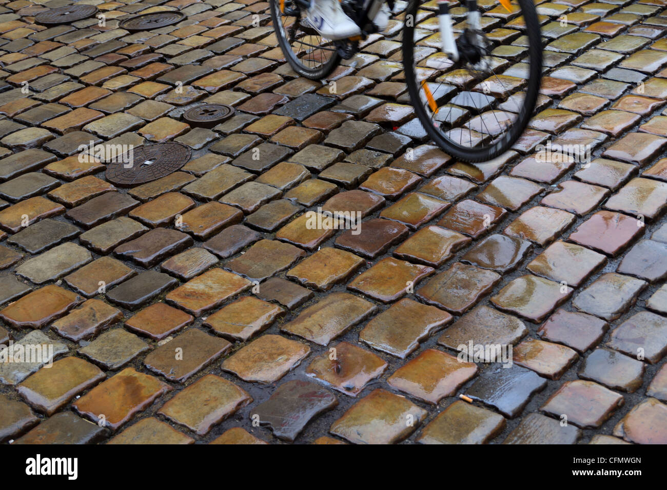 Ciclista su strada bagnata superficie a Praga, Repubblica Ceca Foto Stock