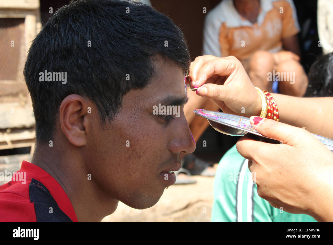 Un giovane uomo nepalese sta diventando tika da sua sorella durante il festival di Tihar è uno dei più importanti festival indù in Nepal Foto Stock