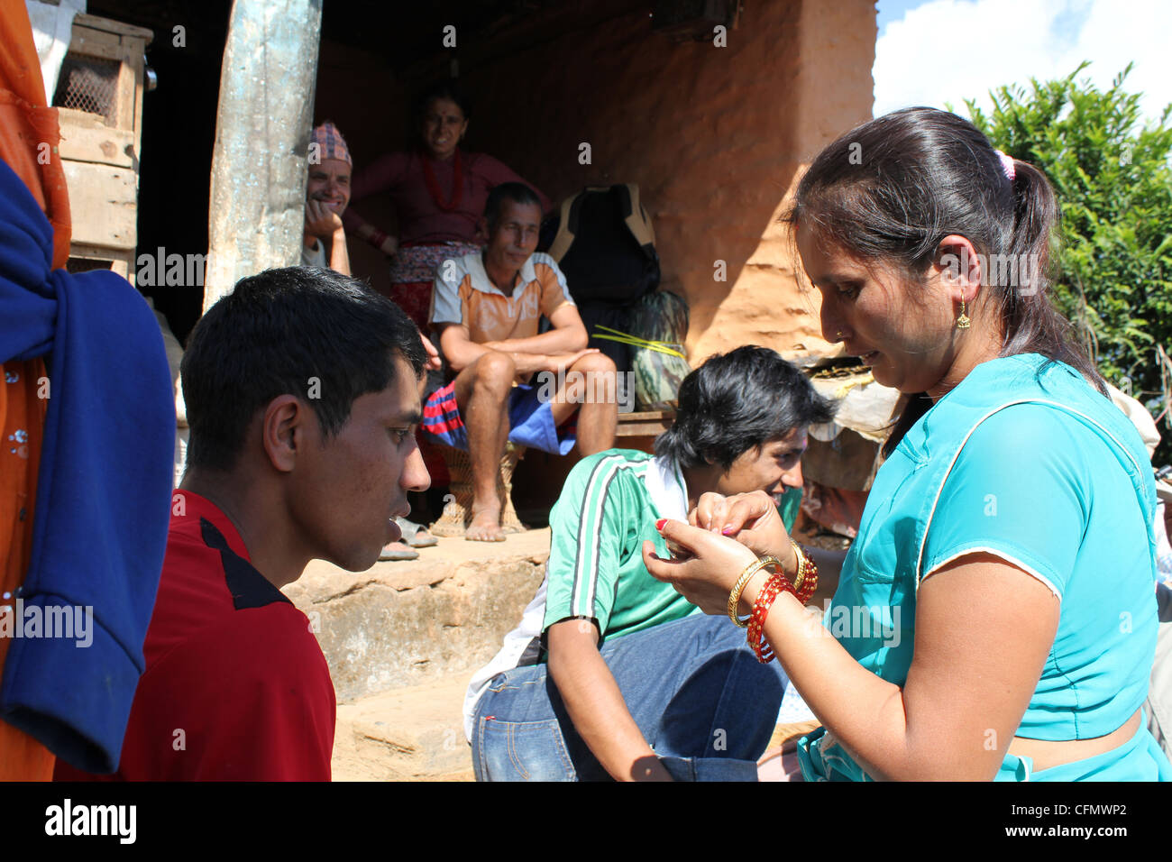 Un uomo nepalese sta diventando una tika da sua sorella durante Tihar è la famiglia è guardare in background Foto Stock