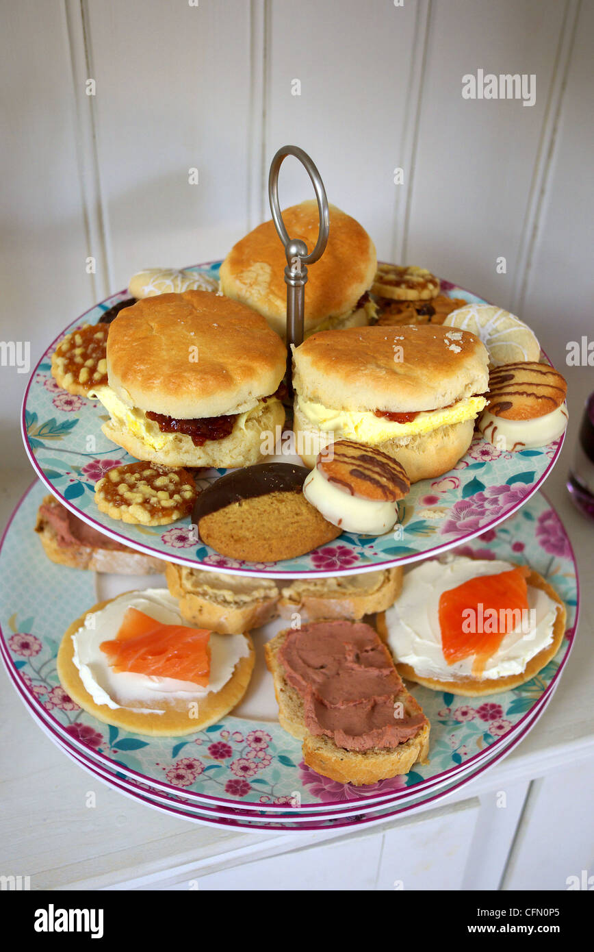 High tea. Una selezione di torte e aprire i panini su una torta a più livelli di stand. Foto Stock