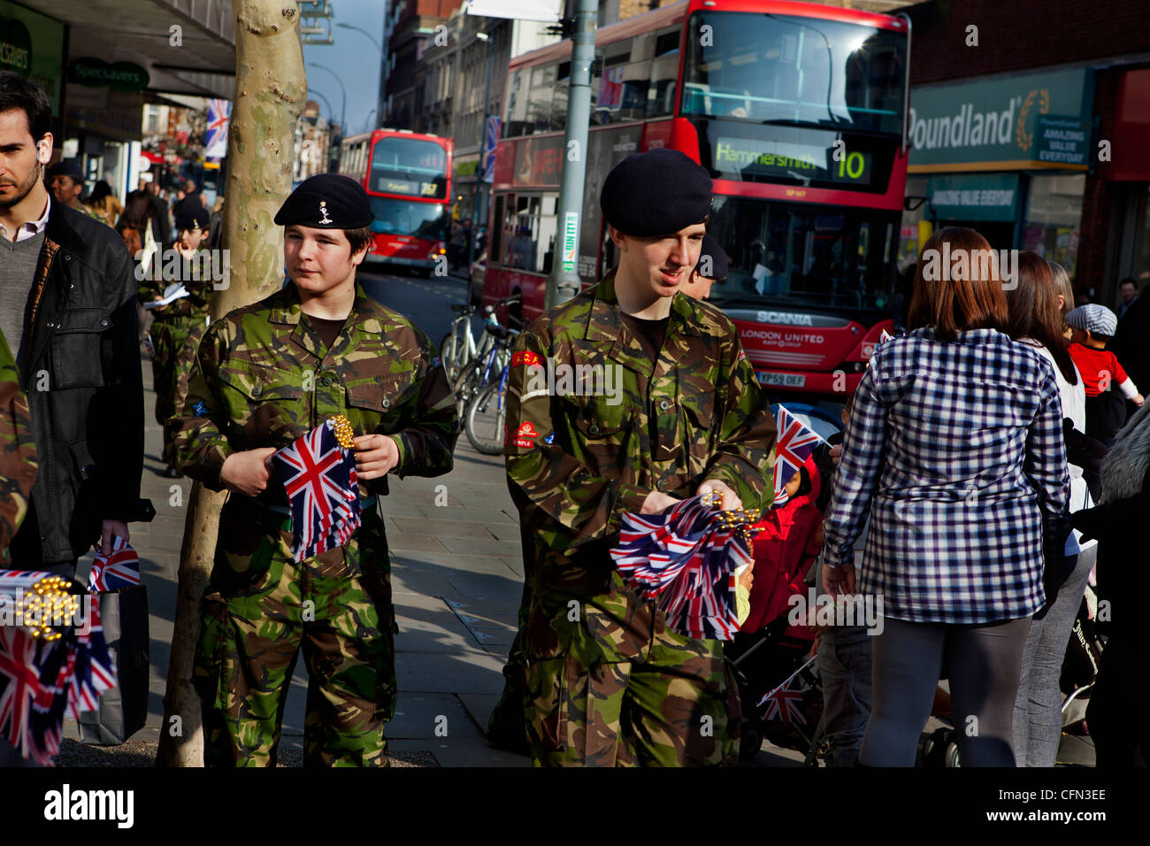 Parte dell'esercito di tempo cadetti dando fuori Unione Jack flag per gli acquirenti prima di una parata militare Foto Stock