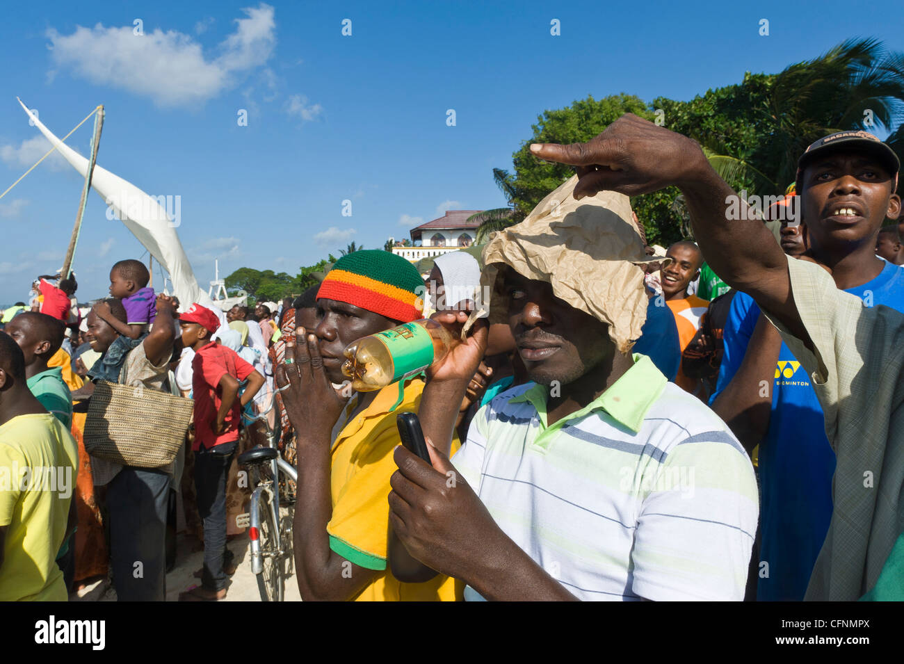 Gli spettatori a guardare una regata di 'Ngalawa tradizionali di out-rigger barche da pesca in Stone Town Zanzibar Tanzania Foto Stock