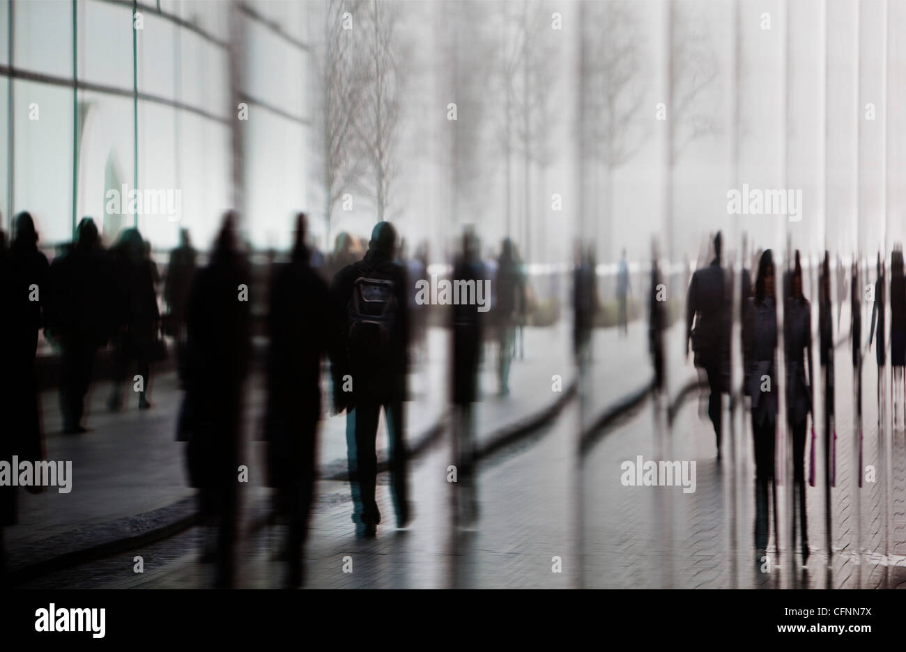 La riflessione di pendolari a piedi attraverso gli edifici di più di Londra area di sviluppo nella nebbia mattutina Foto Stock