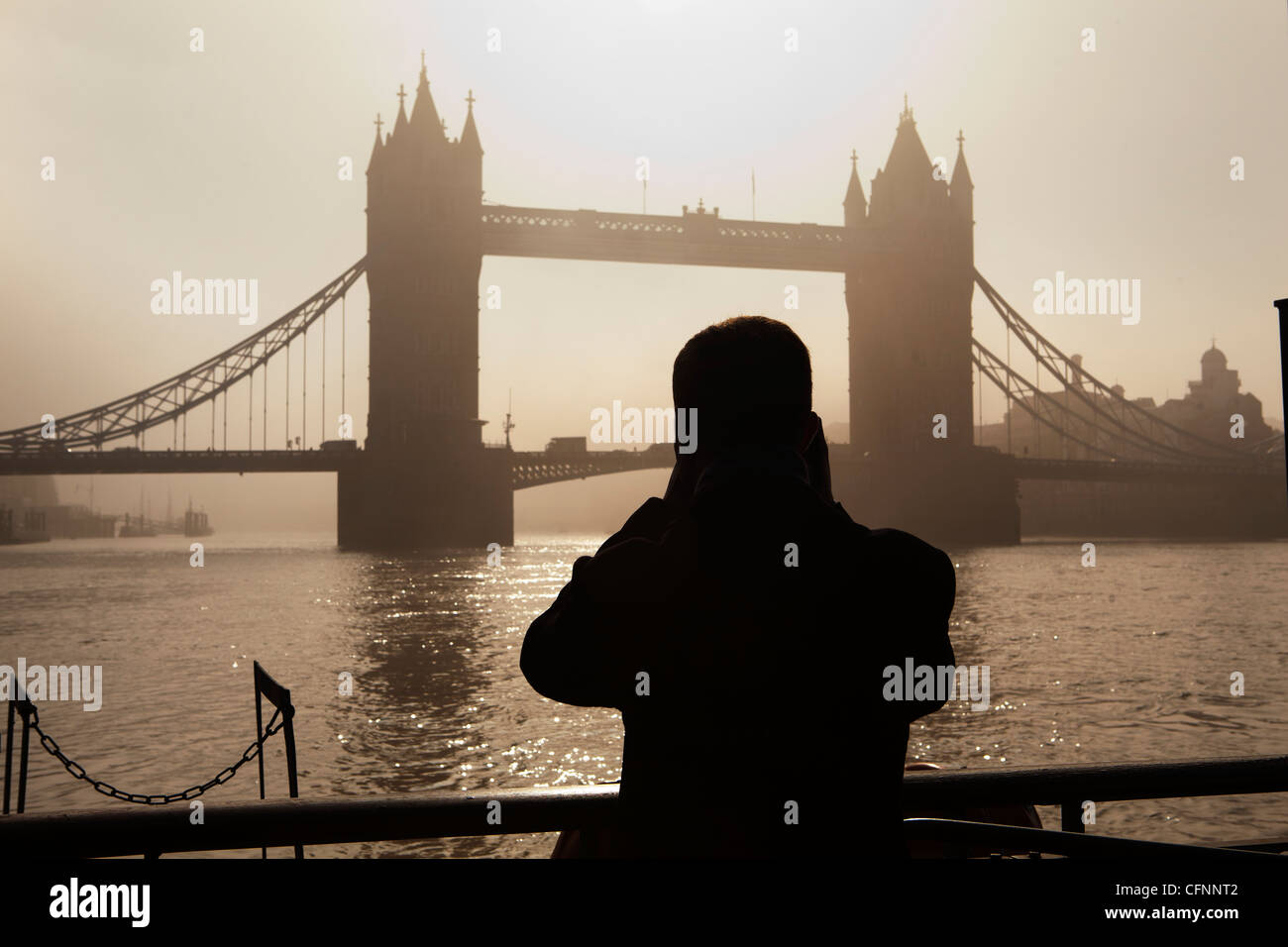 La silhouette di un turista prendere una fotografia del Tower Bridge all'alba Foto Stock