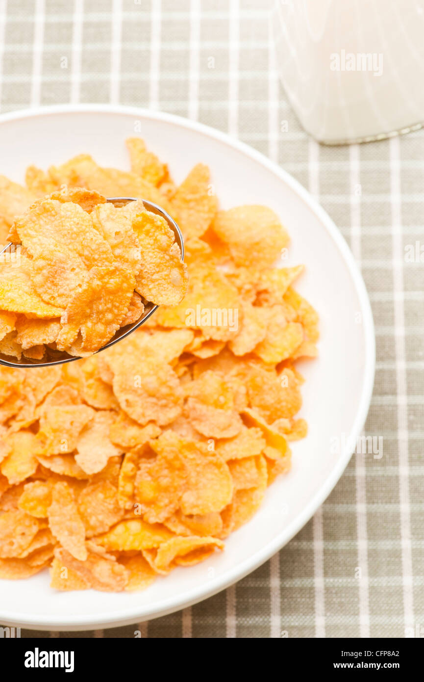 Ciotola riempita con fiocchi di mais e una bottiglia di latte Foto Stock