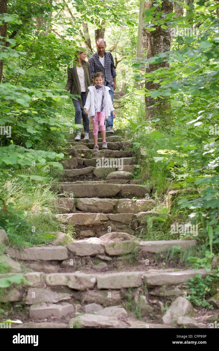 Famiglia camminando giù pietra passi nei boschi Foto Stock