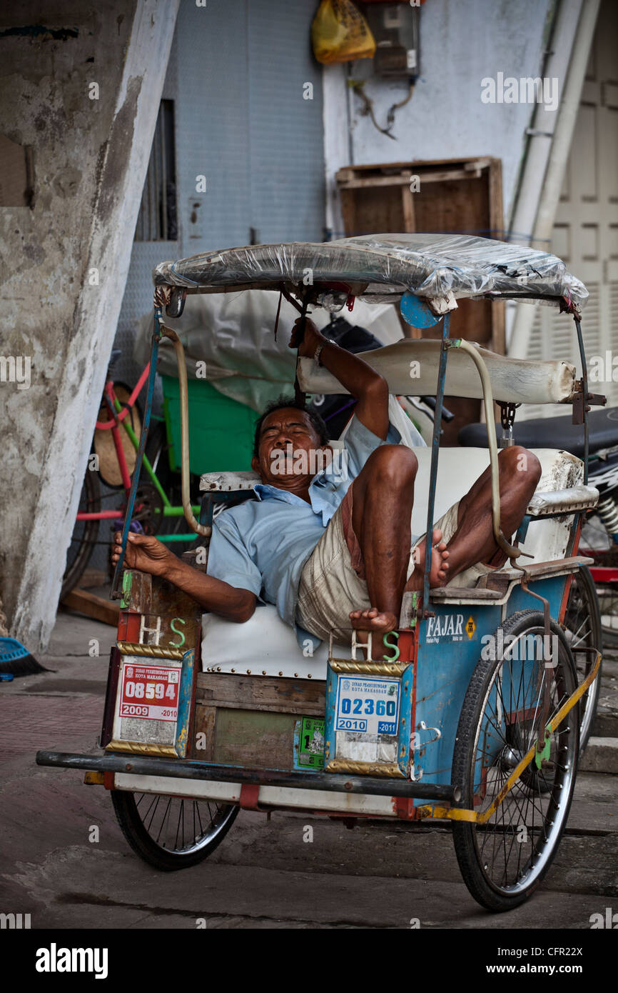 Autista dormire nel suo taxi rickshaw (triciclo) in Makassar, Sulawesi, Java, Bali, South Pacific Indonesia Asia sud-orientale. Foto Stock
