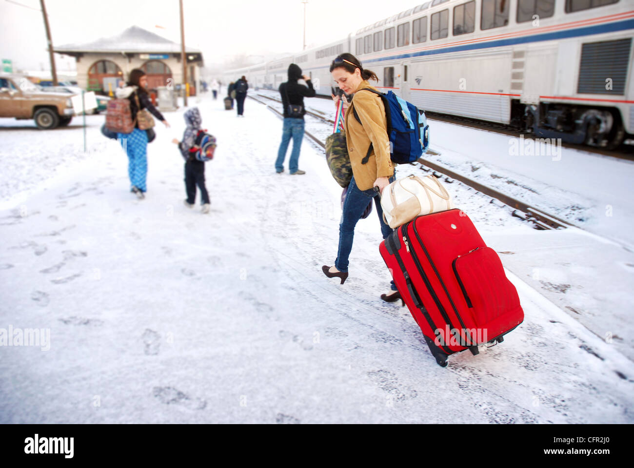 Donna tirando i bagagli attraverso la neve dopo deboarding un treno Amtrak in Oregon Foto Stock