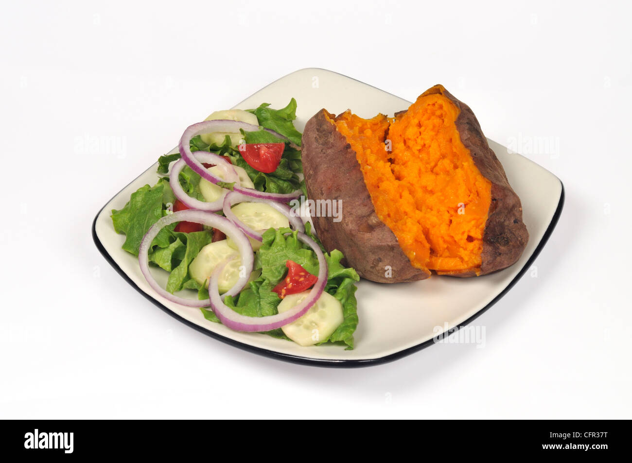 Cuocere al forno yam patata dolce tagliato a metà con burro fuso e insalata di giardino sulla piastra bianca su sfondo bianco tagliato fuori Foto Stock