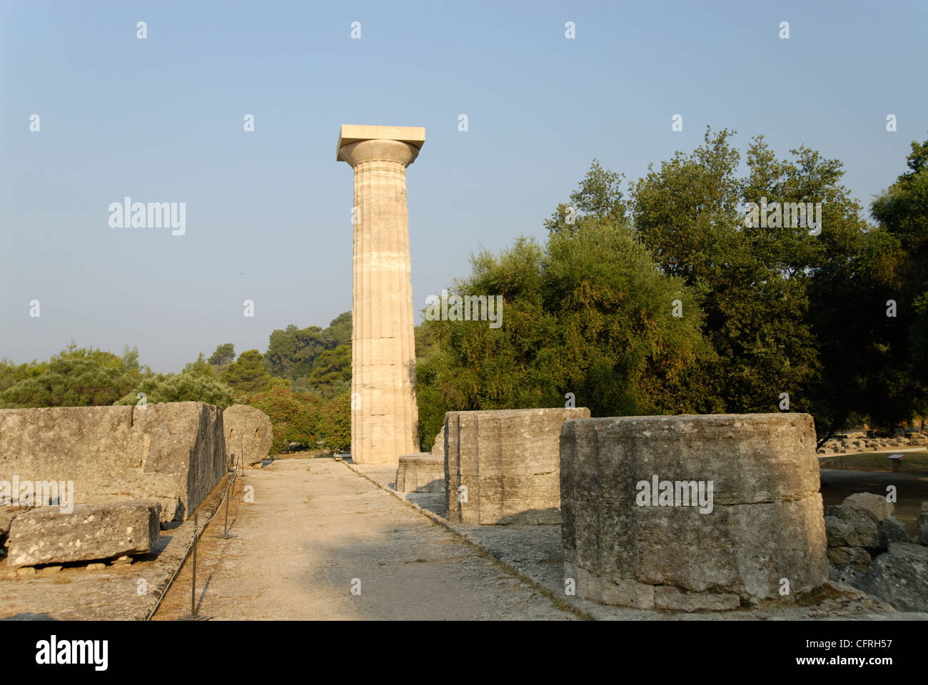 Vista di una ricostruzione di una colonna di solitario tra le massicce rovine della grande del V secolo il tempio di Zeus ad Olimpia. La Grecia. Foto Stock