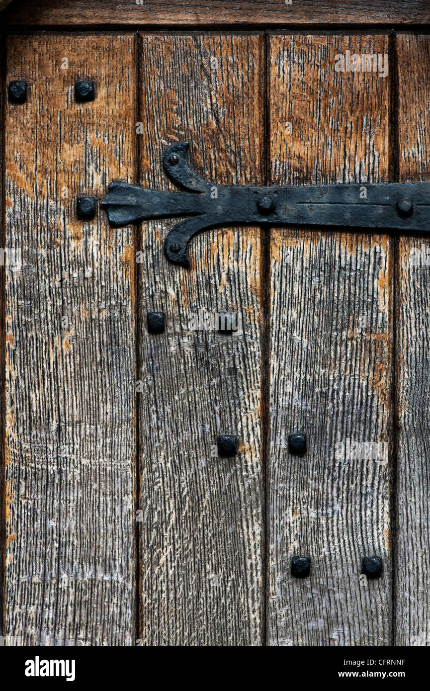 Antica porta in legno di quercia con letti in ferro battuto con cerniera e chiodi abstract Foto Stock
