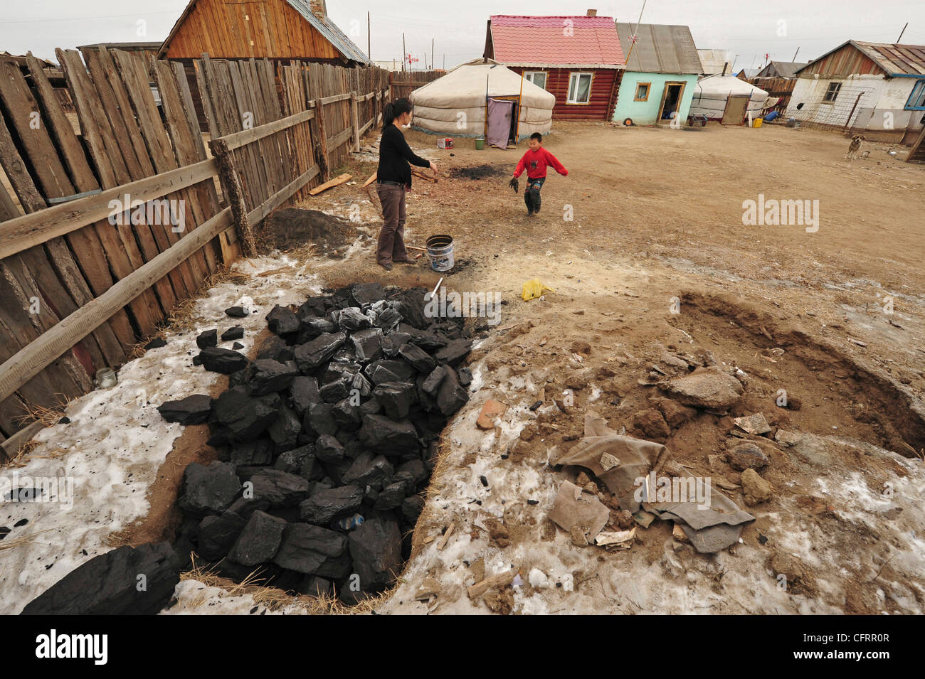 Mongolia, quartiere Baganuur entroterra, metà donna adulta indossando i guanti per raccogliere il carbone, yurt e case in background Foto Stock