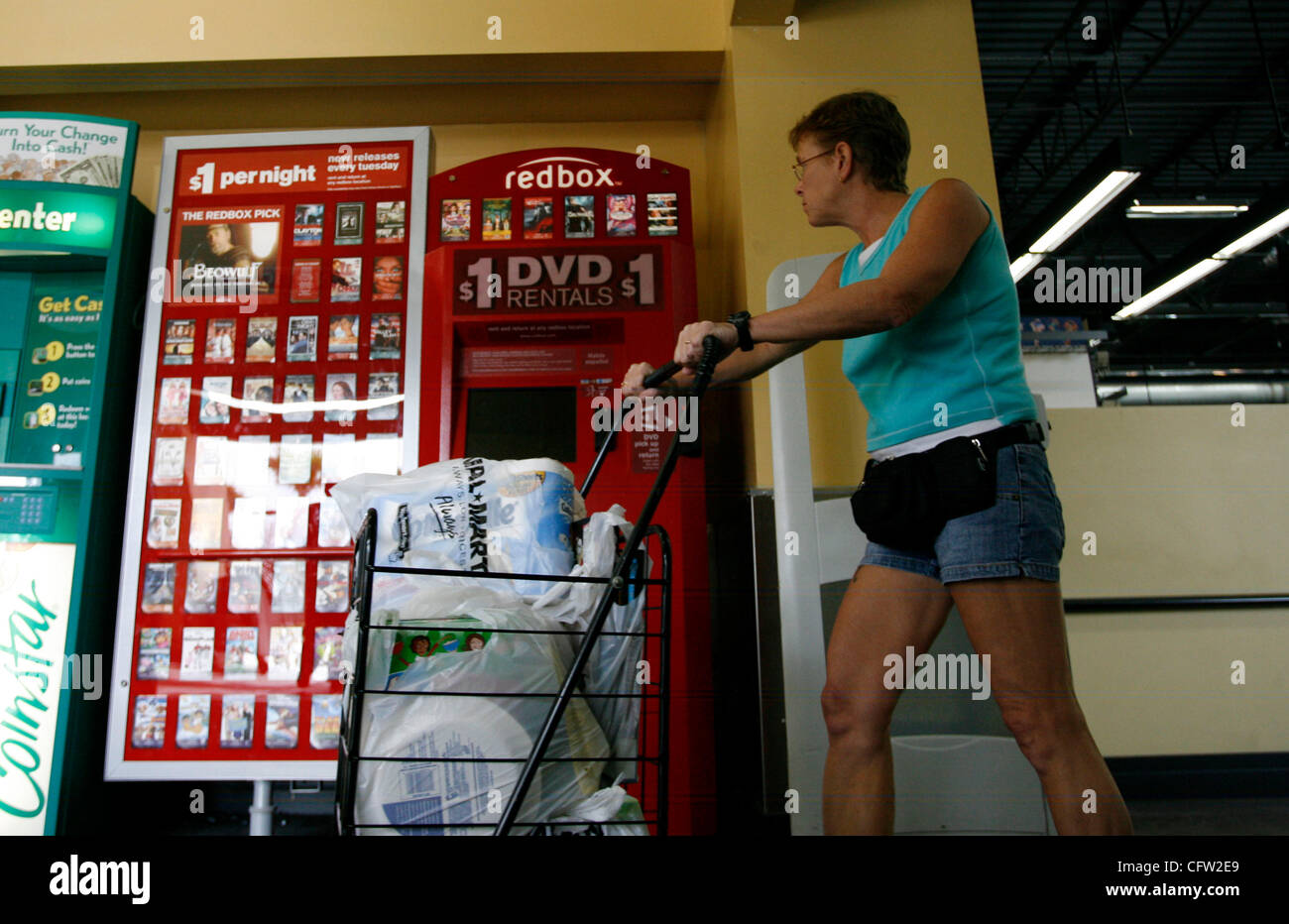 (Tampa 2/26/08)--1) Shoppers presso il Wal-Mart Neigbhrhood Mercato, passare un nuovo riquadro rosso la macchina su Martedì mattina. Casella rossa è un chiosco distributore automatico che si trova mediante la porta a molti esercenti che eroga circa 100 diversi DVD di $ 1 al giorno. Ci sono già più di queste macchine distribuite là fuori Foto Stock