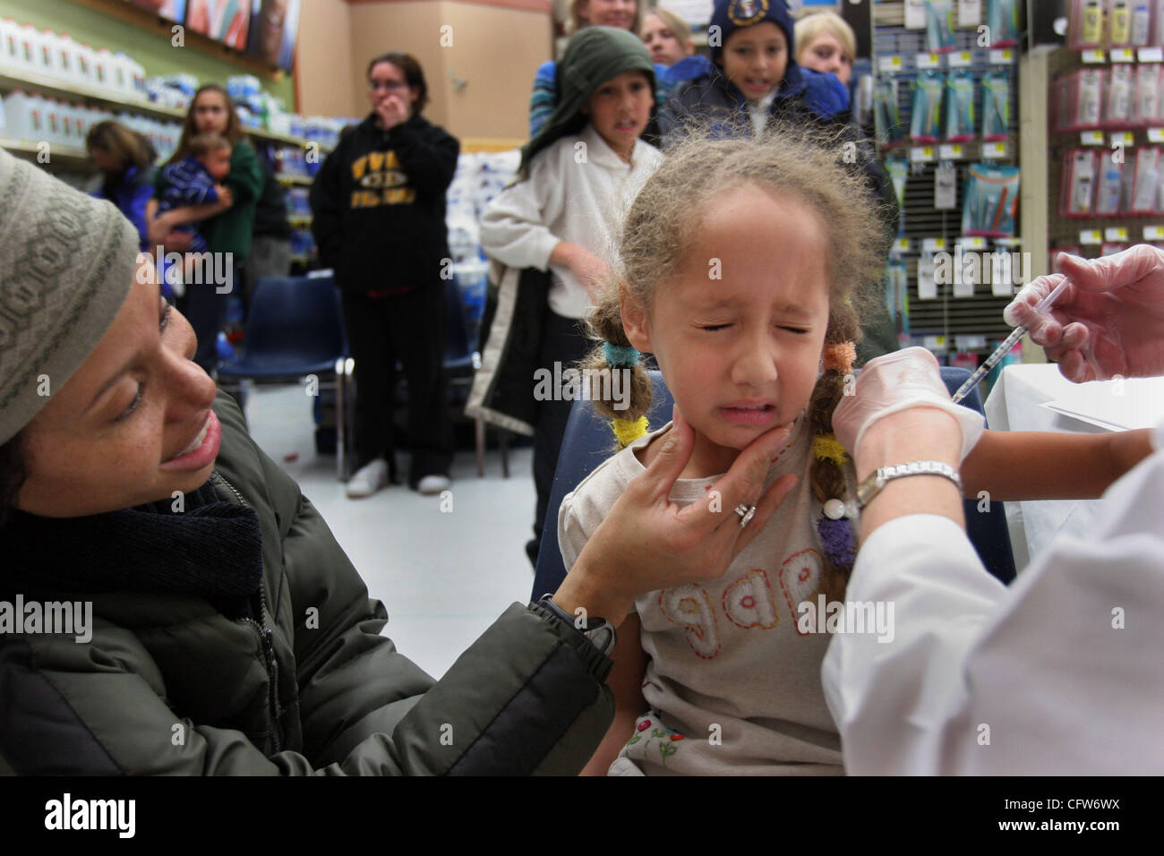 KYNDELL HARKNESS • kharkness@startribune.com Jenny Phillips ha provato a girare i suoi cinque anni di figlia Isabelle Fleming's volto verso di lei come lei ha ricevuto un vaccino antinfluenzale a Cub alimenti nel sud di Minneapolis. Fratelli Samuel e Maxwell stava dietro di lei con simpatia i dolori come hanno aspettato il loro turno. Foto Stock