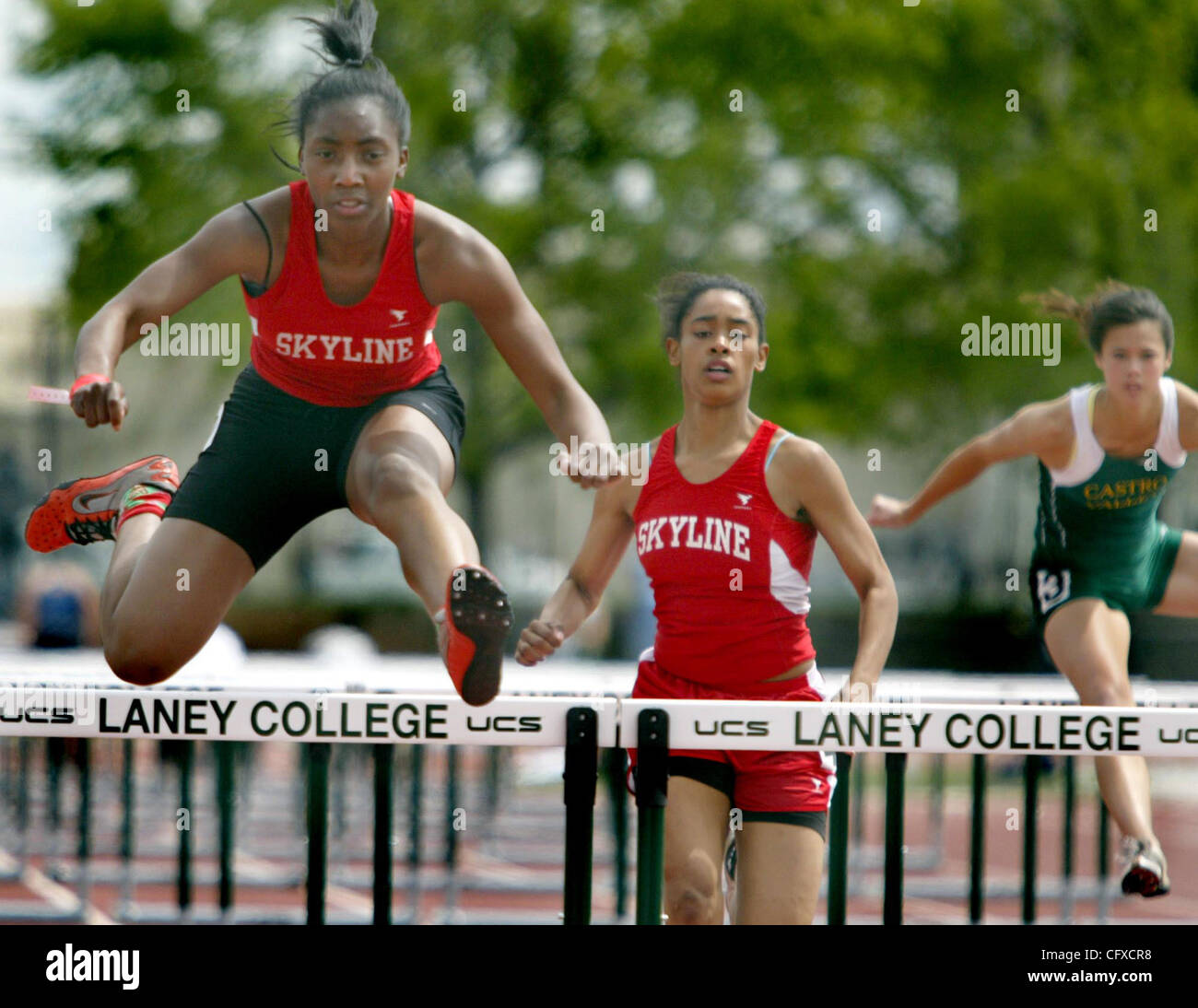 Skyline di Dantia Hudson, sinistra, rende il suo ultimo salto per finsih prima nei 100 metri ostacoli seguito dal compagno atleta Asha Treadwell, centro durante la XXVIII annuale di Oakland Invitational relè al Laney College di Oakland, California, Sabato Apr.7, 2007. (Ray Chavez/Oakland Tribune) Foto Stock