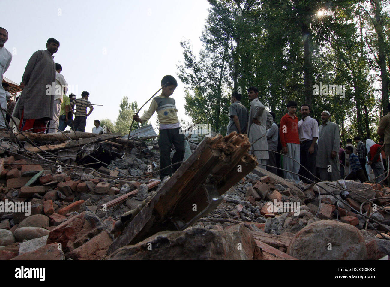 Gli abitanti di un villaggio del Kashmir valutare i danni a una casa dopo un gunbattle tra l'esercito indiano e presunti militanti Saloora, 25 km (16 miglia a est di Srinagar, Luglio 5, 2007. Tre militanti sono stati uccisi e una casa residenziale rasa al suolo, con parziale danneggiamento causato anche alcune altre case Foto Stock