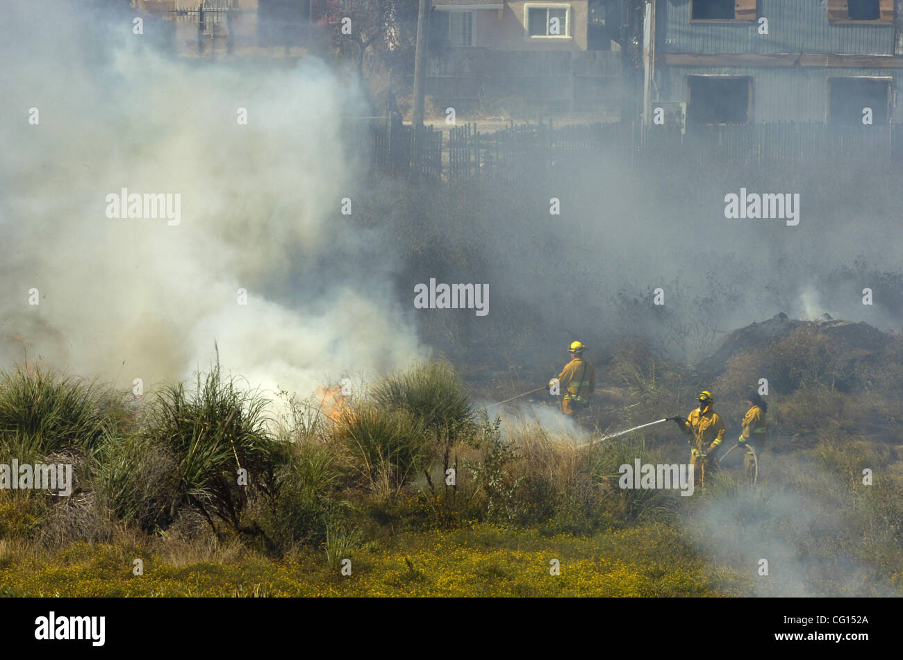 Vigili del fuoco abbattere le ultime fiamme di un fuoco d'erba appena a sud di Vernon Lane in Richmond, Calif. martedì 24 luglio, 2007. (Kristopher Skinner/Contra Costa Times) Foto Stock