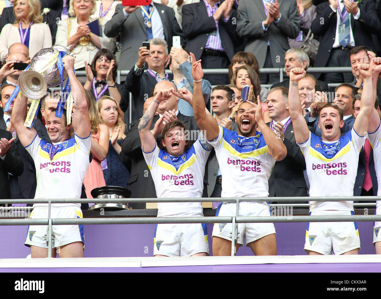 25 ago 2012. Leeds rinoceronti v Warrington Lupi Carnegie Challenge Cup Final 2012 Warrington lupi capitano Adrian Morley solleva il challenge cup con L-R: Lee rovi, Ryan Atkins e Richard Myler Foto Stock