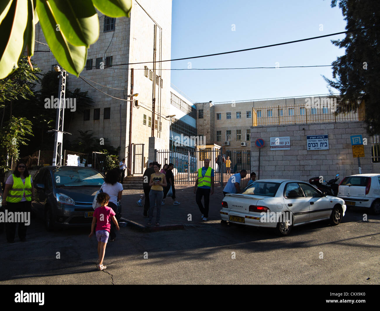Il 27 agosto 2012. I genitori che indossano giubbetti luminosi assistono volontariamente con il monitoraggio del traffico e per permettere agli studenti un accesso sicuro alla Bet-Hakerem Scuola elementare il primo giorno dell anno scolastico. Gerusalemme, Israele. 27-Aug-2012. Bambini israeliani di tornare a scuola oggi, abolendo il tradizionale sett. 1a data, in una prima fase delle riforme avviate dal Ministero dell'istruzione mira ad accorciare le vacanze estive a 6 settimane, parzialmente alleviare i genitori di enormi spese finanziarie. Foto Stock
