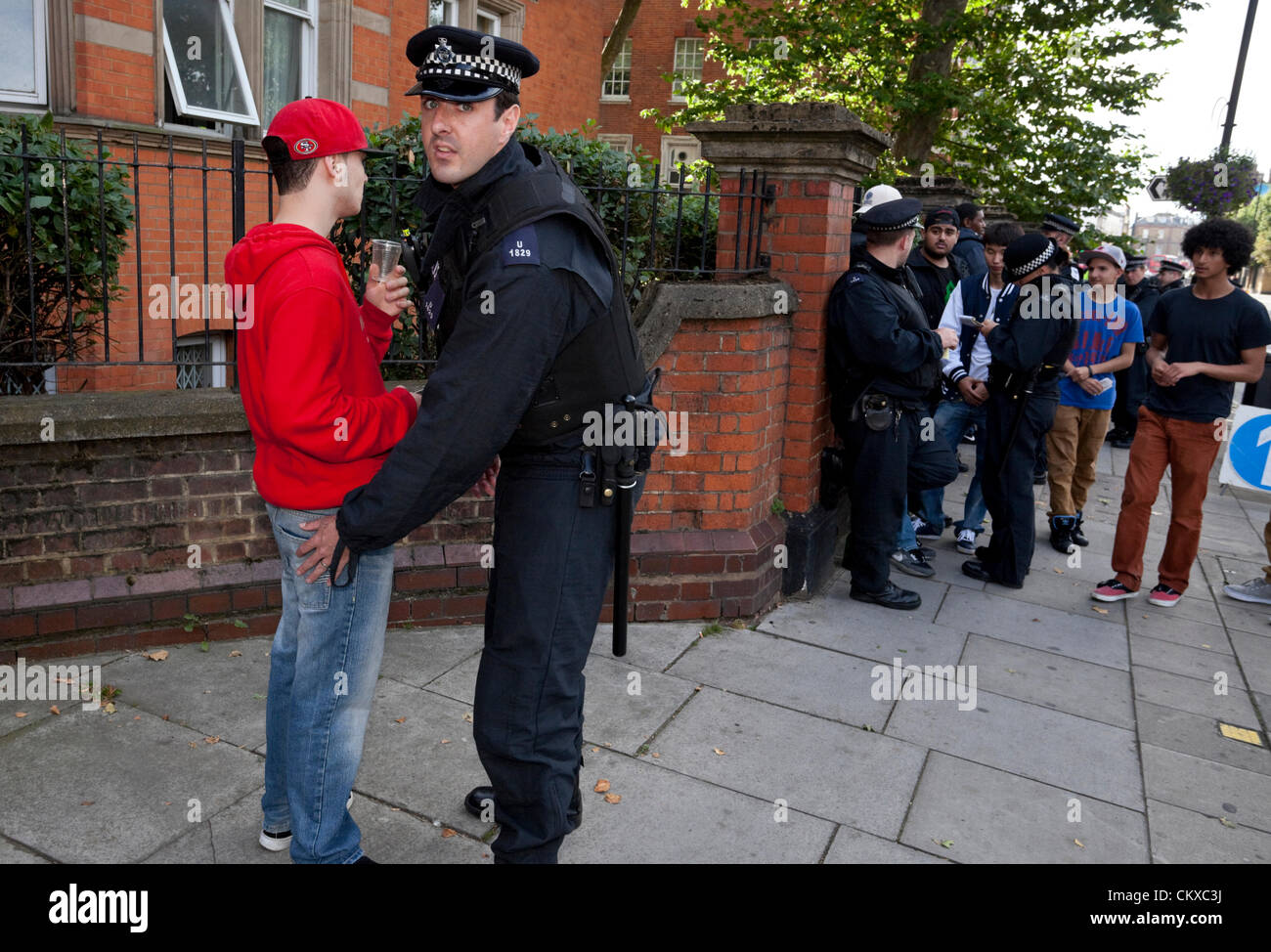 Un gruppo di poliziotti metropolitani si fermano e cercano un gruppo di giovani al Carnevale di Notting Hill. Foto Stock