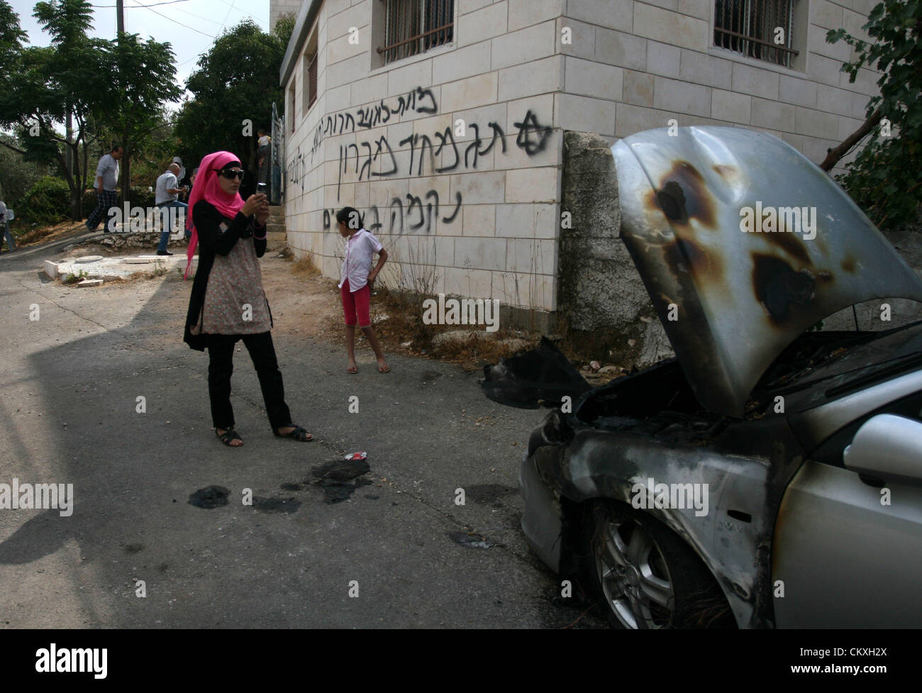 Il 29 agosto 2012 - Ramallah, West Bank, Territorio palestinese - Una donna Palestinese scatta una foto con il suo telefono cellulare di Ebraico graffiti che recita ""morte agli arabi'' e ''Migron'', riferendosi all'insediamento ebraico di Migron, sulla facciata di una casa da vandali credevano di essere gli estremisti ebrei nella West Bank village di Dura Al-Qara, vicino a Ramallah, il 29 agosto 2012 (credito Immagine: © Issam Rimawi APA/images/ZUMAPRESS.com) Foto Stock