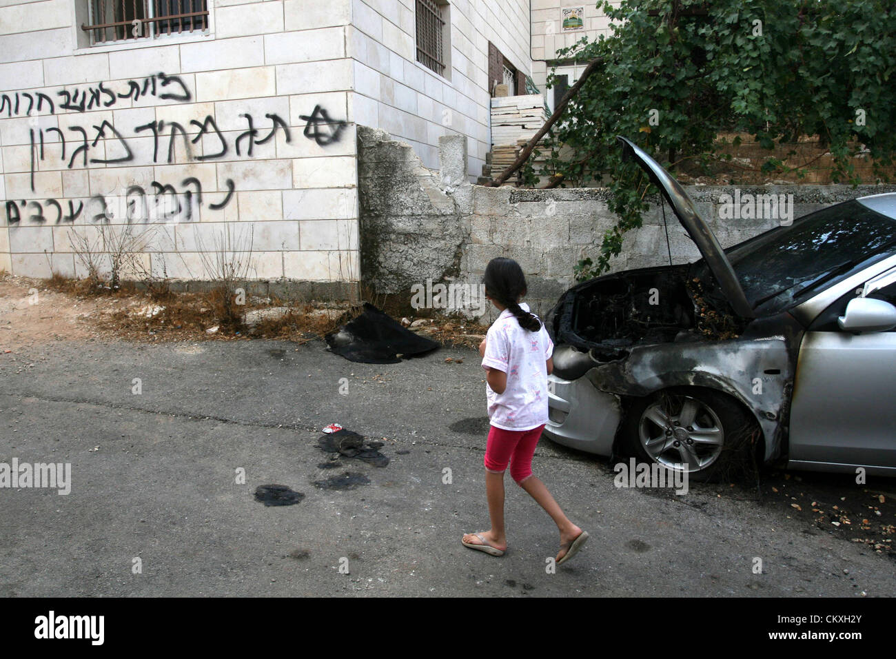 Il 29 agosto 2012 - Ramallah, West Bank, Territorio palestinese - una ragazza palestinese sembra ebraico graffiti che recita ""morte agli arabi'' e ''Migron'', riferendosi all'insediamento ebraico di Migron, sulla facciata di una casa da vandali credevano di essere gli estremisti ebrei nella West Bank village di Dura Al-Qara, vicino a Ramallah, il 29 agosto 2012 (credito Immagine: © Issam Rimawi APA/images/ZUMAPRESS.com) Foto Stock