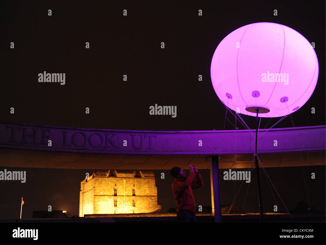 La spia di collegamento installazione d arte da New York basata arti digitali YesYesNo collettiva. Alcuni 400 tempo palloncini con impulsi di luci LED colorate sono stati installati in vari siti attraverso i 73 chilometri di muro di Adriano. Qui un membro del pubblico viste una delle luci posizionata sulla rotonda a Tullie House Galleria d'arte e museo a Carlisle, Cumbria che insieme a Carlisle Castle si trova vicino alla linea del Muro di Adriano Foto Stock