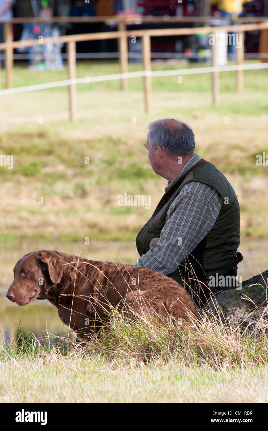 15.09.2012. La Midland Game Fair a Weston Park, Shropshire, Regno Unito. Un uomo si siede con un cane. Foto Stock