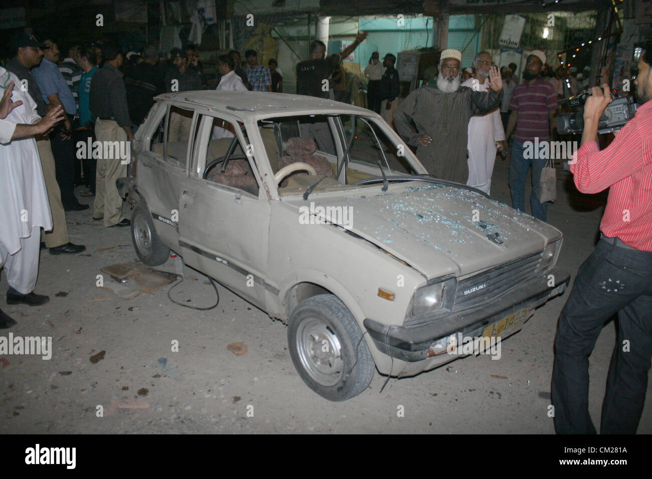 Le persone si radunano nei pressi di relitti di auto dopo aver attentato alla zona Hyderi a Karachi il Martedì, Settembre 18, 2012. Foto Stock