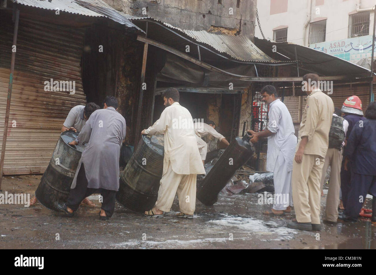 Rimuovere persone tamburi e cilindri da una bombola di gas il negozio dove una esplosione è avvenuta nella zona Kharadar, a Karachi il lunedì, 24 settembre 2012. (S.Imran Foto Stock