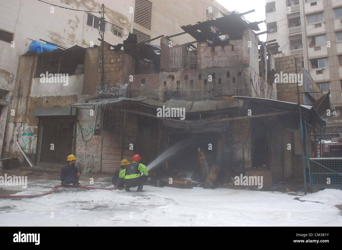 Vigili del fuoco funzionari l'estinzione incendio scoppiato dopo una bombola di gas blast in un negozio in zona Kharadar a Karachi il lunedì, 24 settembre 2012. Foto Stock