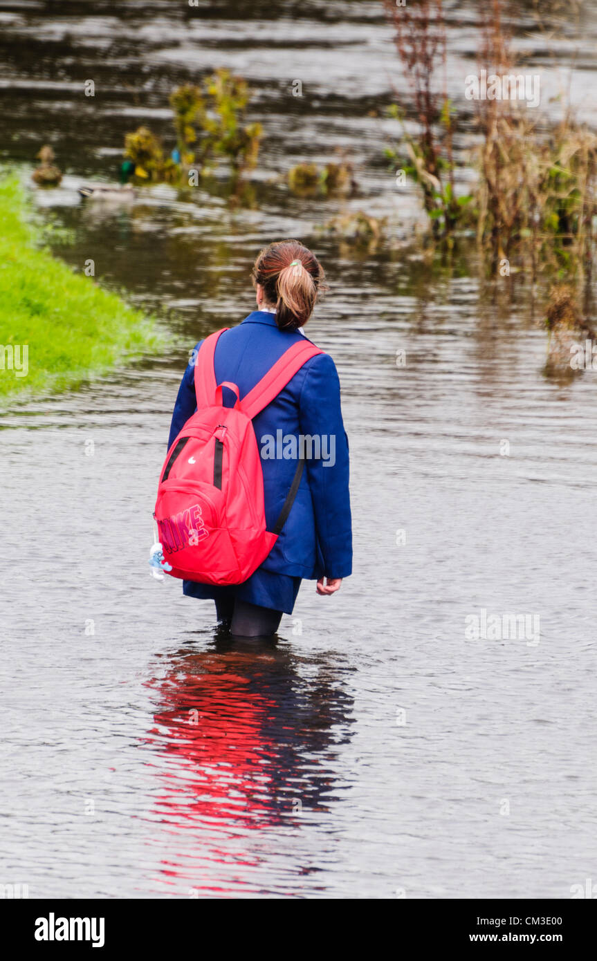 Schoolgirl wades attraverso acqua dopo il solo cammino home è sommersa dall'alluvione Foto Stock