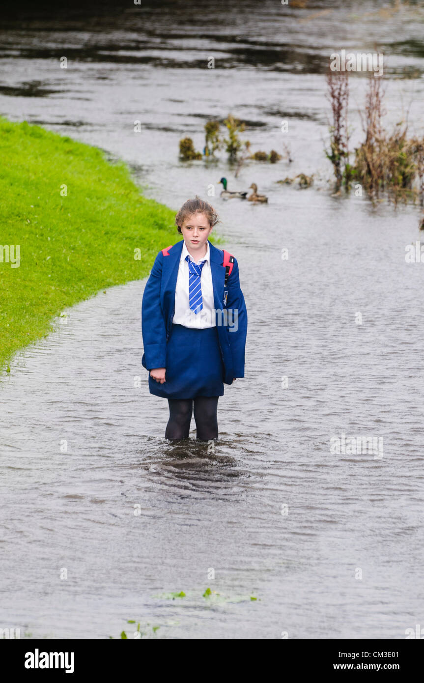 Schoolgirl wades attraverso acqua dopo il solo cammino home è sommersa dall'alluvione Foto Stock