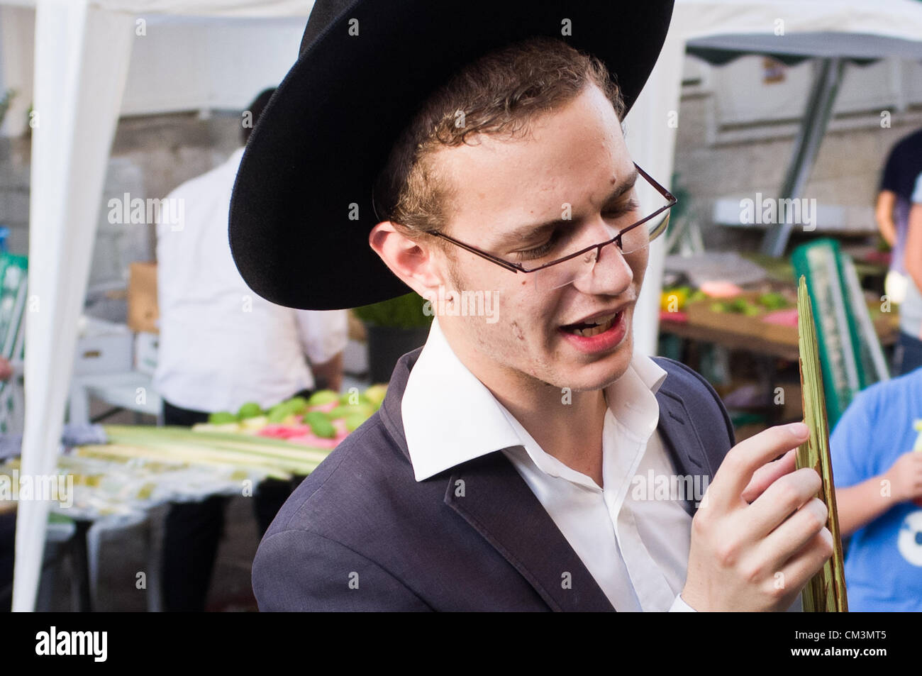 Un giovane uomo meticolosamente ispeziona i bordi di un lulav, mature, verde, frond chiusa da una data struttura Palm Tree e una delle quattro specie al Bait-Vagan quattro specie mercato. Gerusalemme, Israele. 27-Settembre-2012. Con Yom Kippur oltre, preparazioni immediatamente iniziare per Sukkot, la Festa dei Tabernacoli. Gli Ebrei religiosi ispezionare e acquistare il 'Quattro specie ", come ordinato in Levitico 23:40. Qualsiasi lieve imperfezione invalida la frutta. Foto Stock