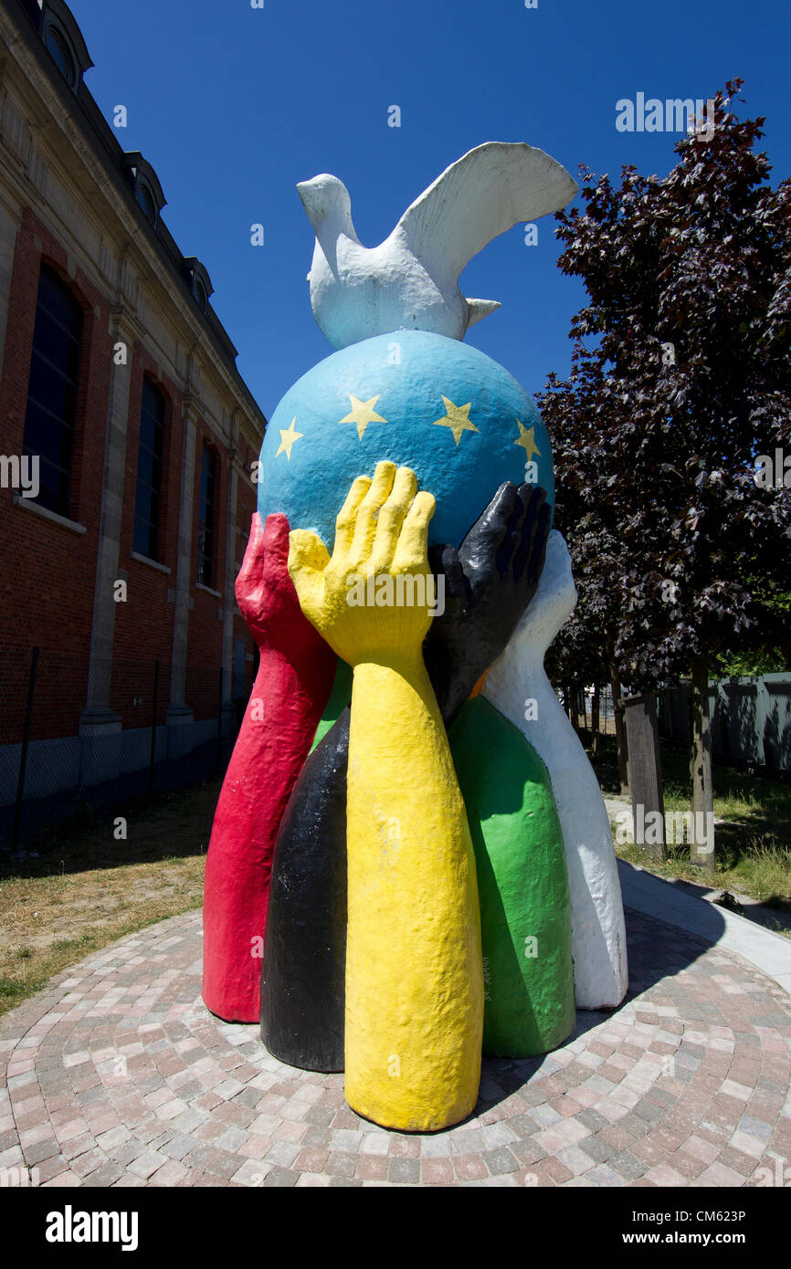 Statua di pace di un mondo dipinto con la bandiera dell'UE e una colomba della pace si erge nel giardino di una chiesa vicino al Consiglio UE a Bruxelles Foto Stock
